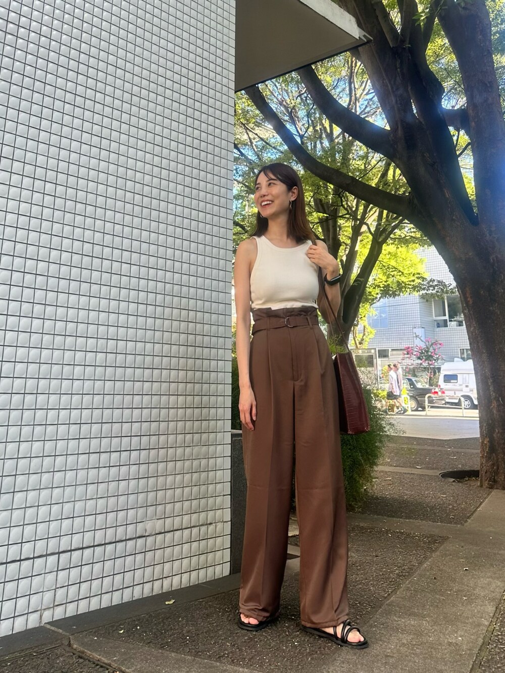 ホワイト系のタンクトップ、ブラウン系のパンツ、ブラック系のサンダルを着用したレディースの夏コーディネートの2枚目の写真