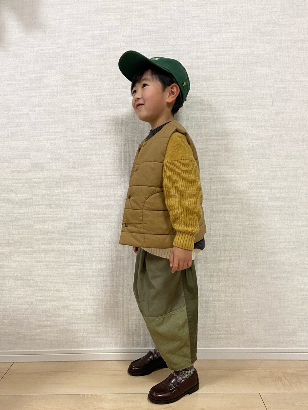 グレー系のニット/セーター、グリーン系のその他パンツ、ブラウン系のベストを着用したキッズの冬コーディネートの2枚目の写真