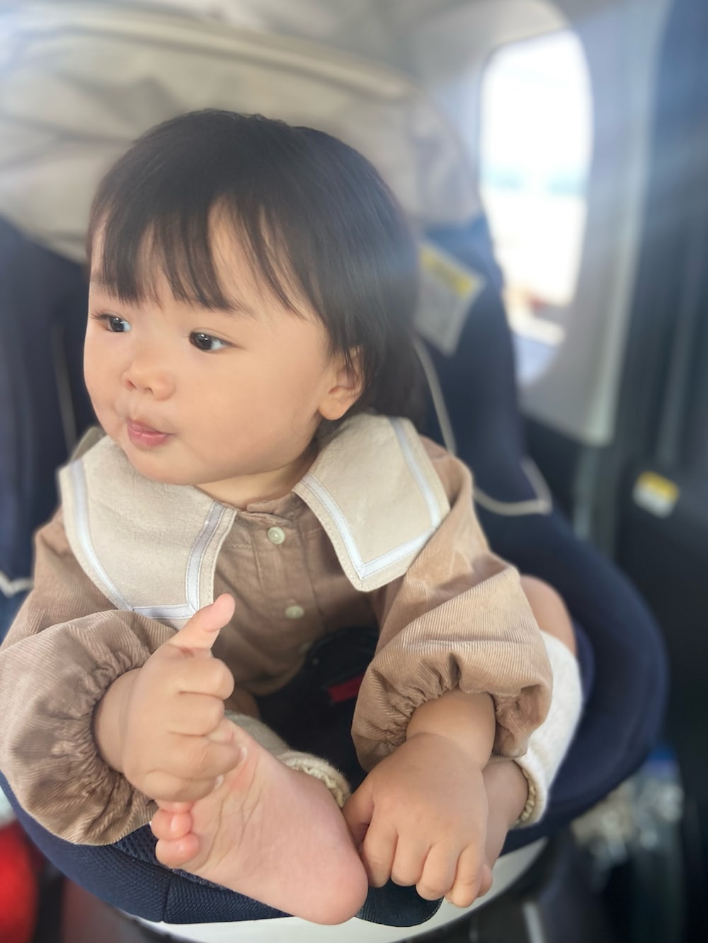 ブラウン系のロンパース、ベージュ系のママ＆ベビー、ホワイト系のレッグウォーマーを着用したキッズの秋コーディネートの2枚目の写真