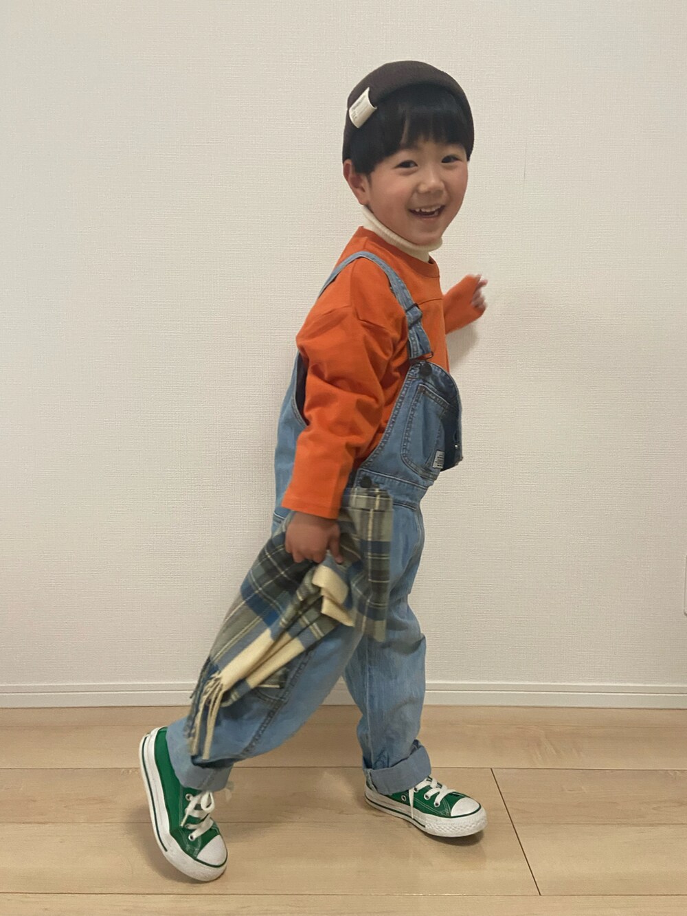 オレンジ系のTシャツ/カットソー、ブルー系のサロペット/オーバーオール、ホワイト系のニット/セーターを着用したキッズの冬コーディネートの4枚目の写真