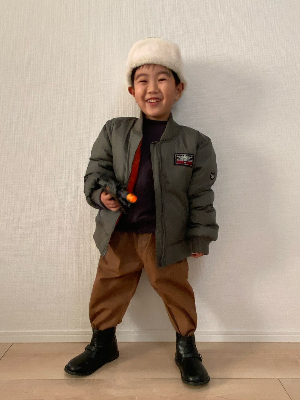 ブラック系のスウェット、ブラウン系のチノパンツ、グリーン系のMA-1を着用したキッズの秋コーディネートの3枚目の写真