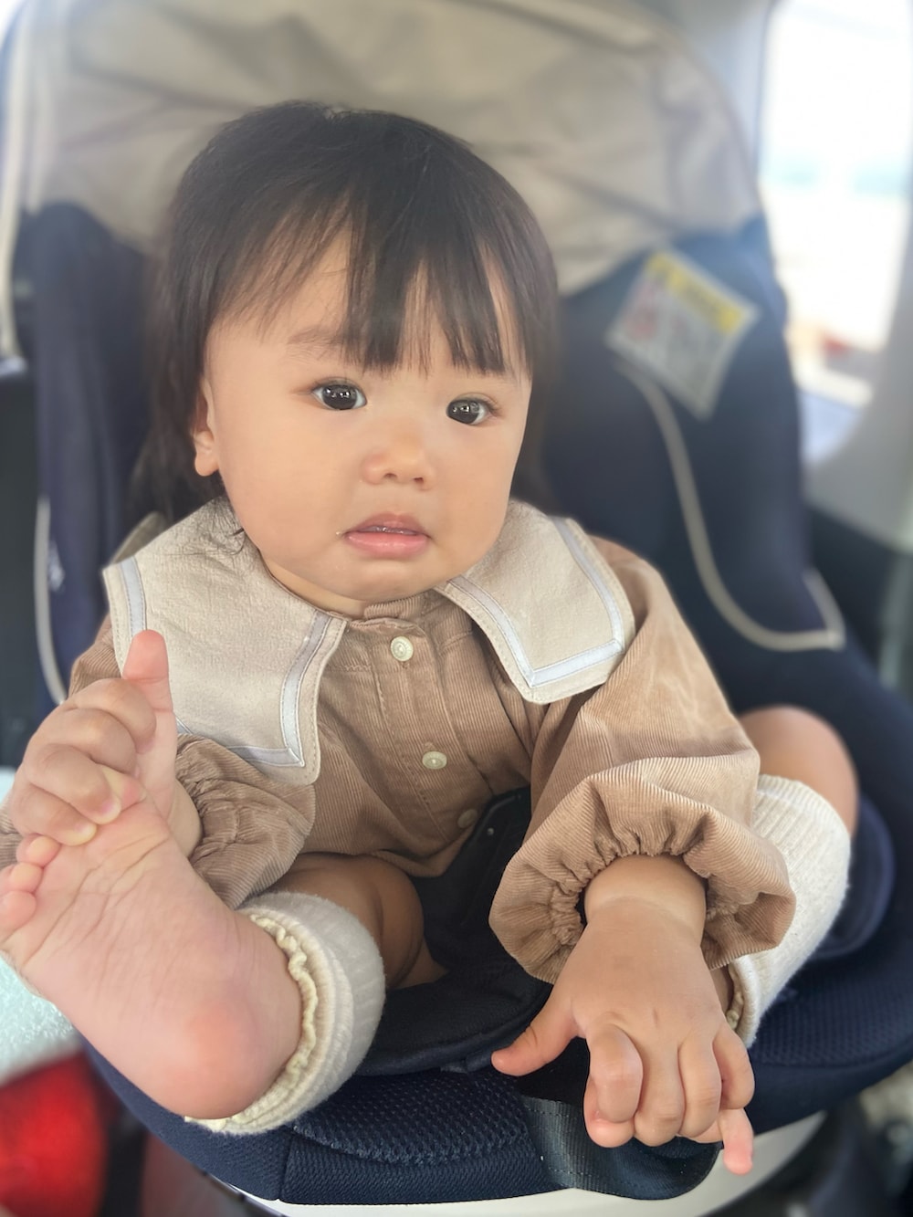 ブラウン系のロンパース、ベージュ系のママ＆ベビー、ホワイト系のレッグウォーマーを着用したキッズの秋コーディネートの3枚目の写真