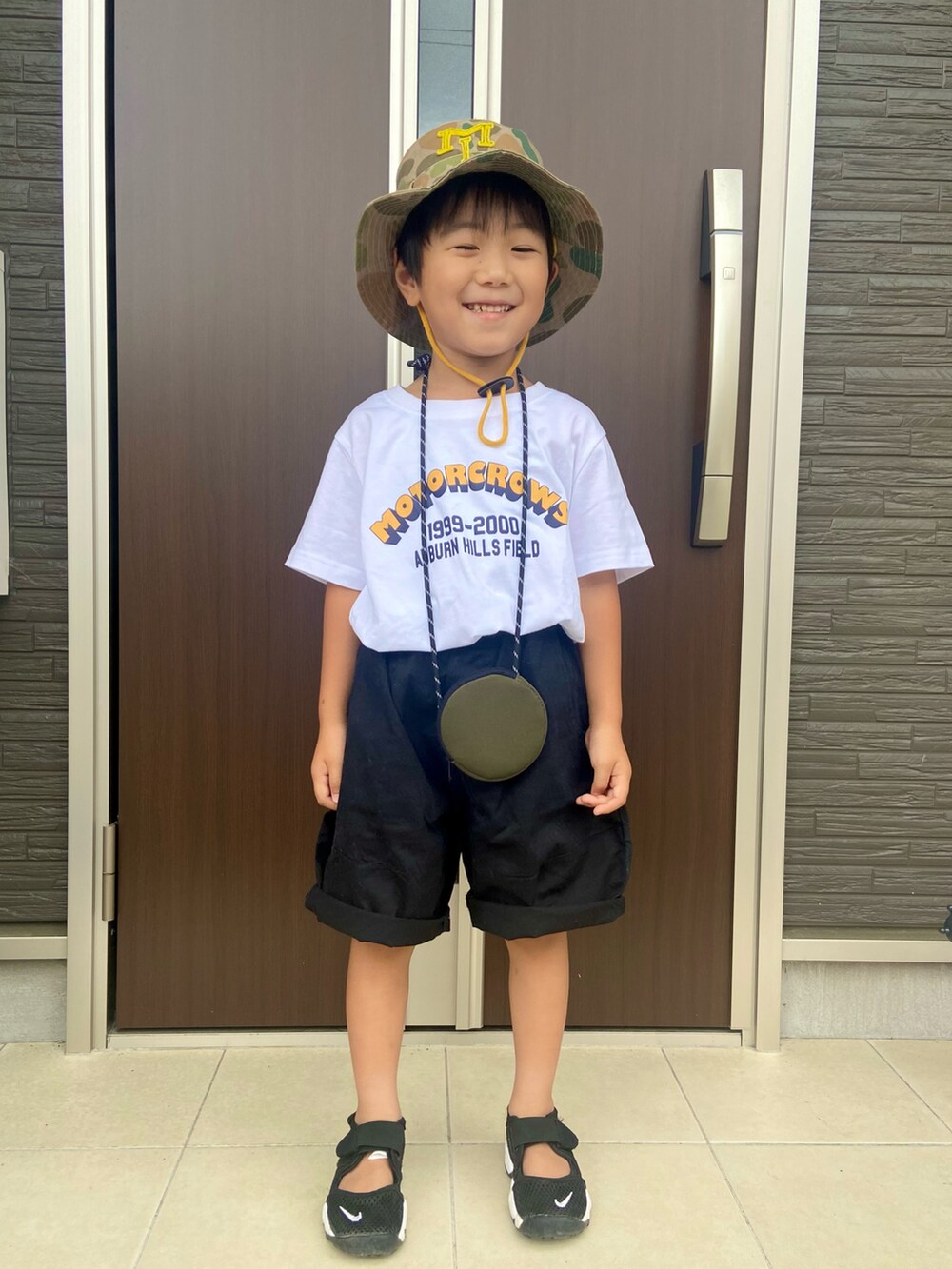 ホワイト系のTシャツ/カットソー、ブラック系のチノパンツ、ブラック系のサンダルを着用したキッズの夏コーディネートの2枚目の写真
