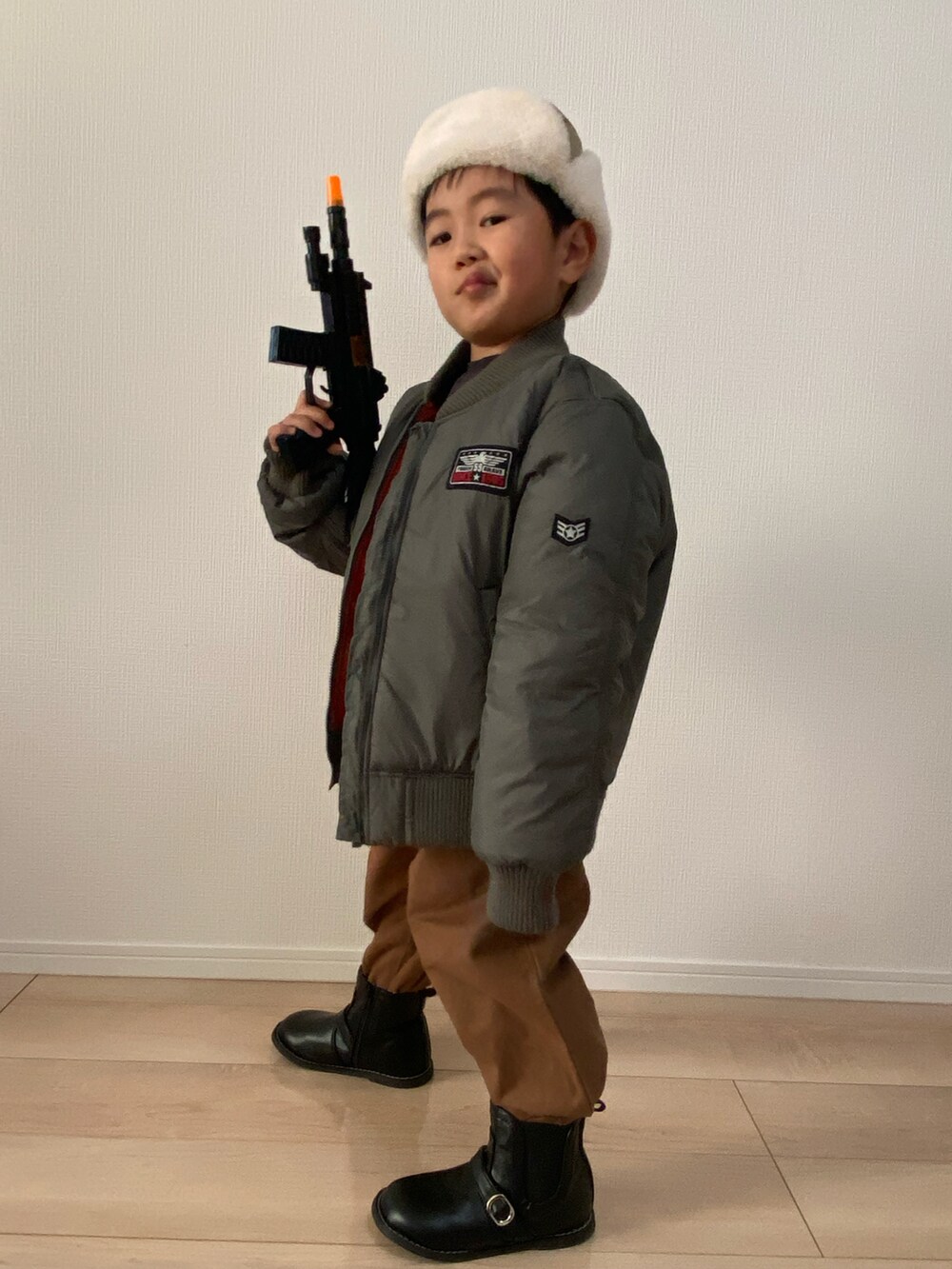 ブラック系のスウェット、ブラウン系のチノパンツ、グリーン系のMA-1を着用したキッズの秋コーディネートの5枚目の写真