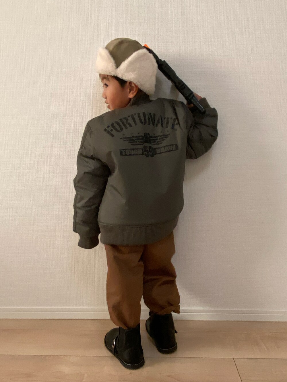 ブラック系のスウェット、ブラウン系のチノパンツ、グリーン系のMA-1を着用したキッズの秋コーディネートの2枚目の写真