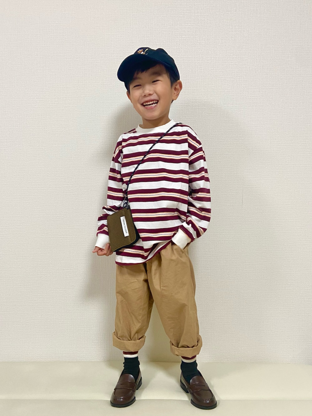 レッド系のTシャツ/カットソー、ベージュ系のその他パンツ、ブラウン系のローファーを着用したキッズの秋コーディネートの2枚目の写真
