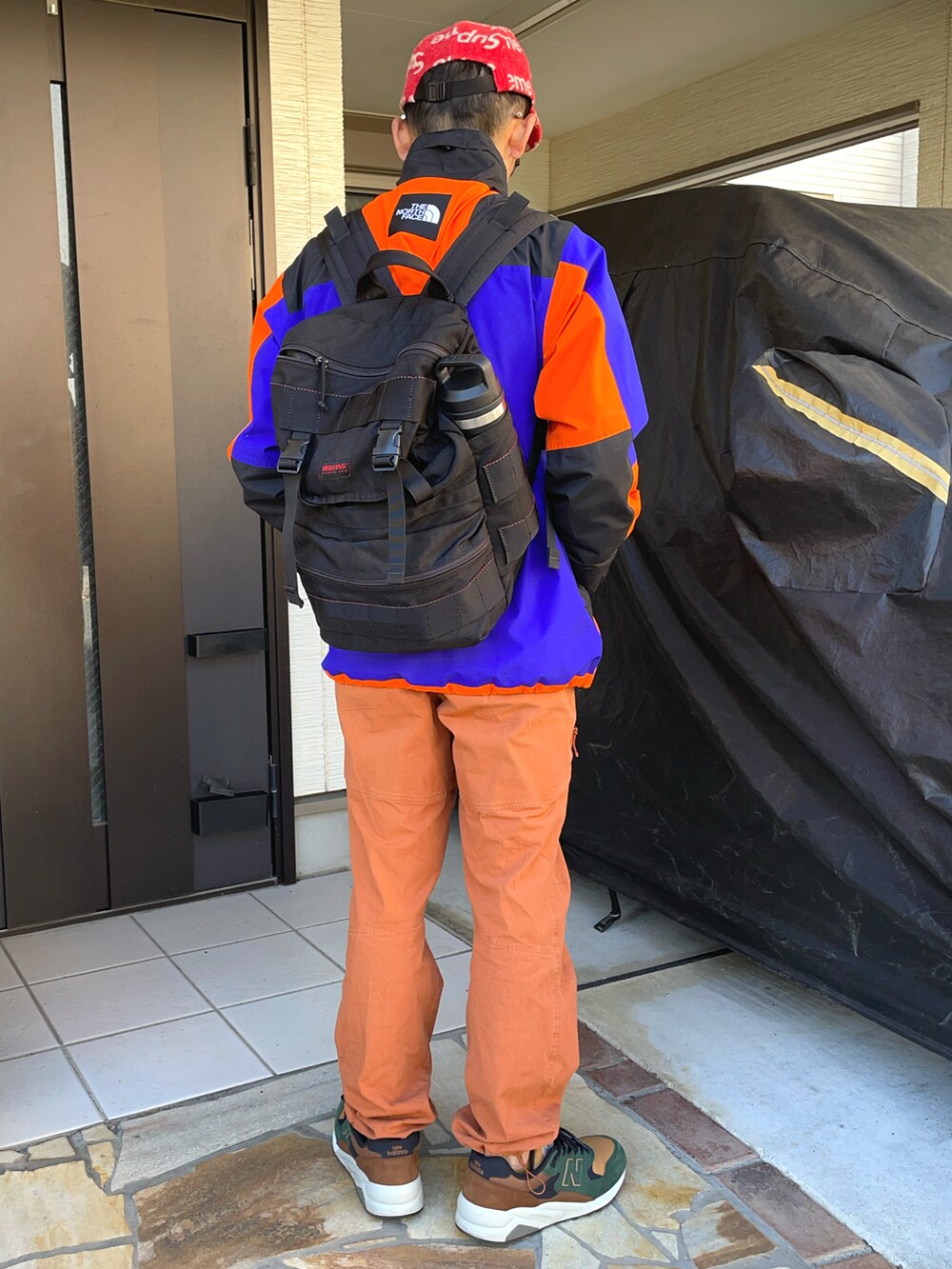 オレンジ系のナイロンジャケット、ブラウン系のブルゾン、オレンジ系のカーゴパンツを着用したメンズの冬コーディネートの2枚目の写真