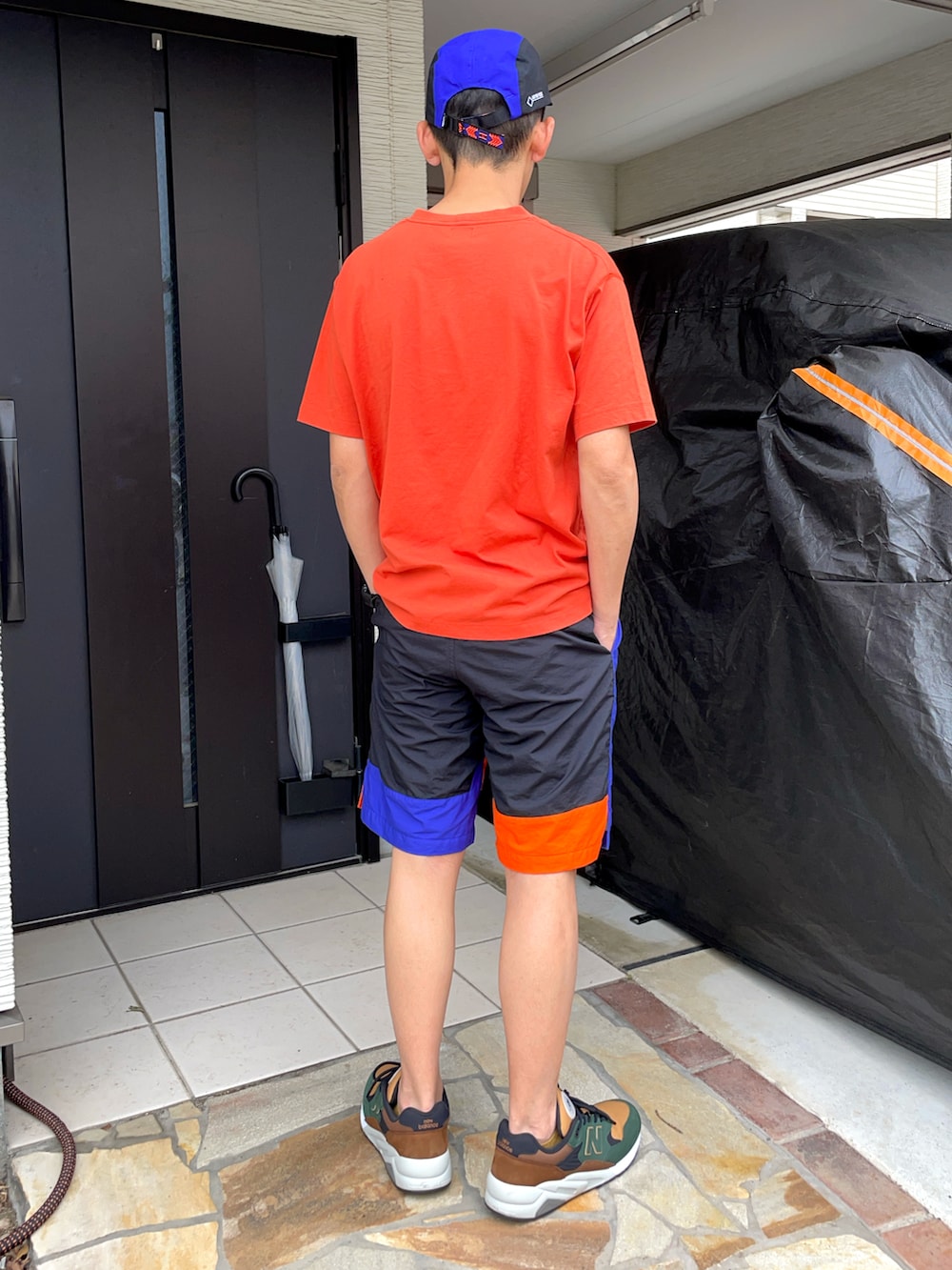 オレンジ系のTシャツ/カットソー、オレンジ系のパンツ、グリーン系のスニーカーを着用したメンズの春コーディネートの2枚目の写真