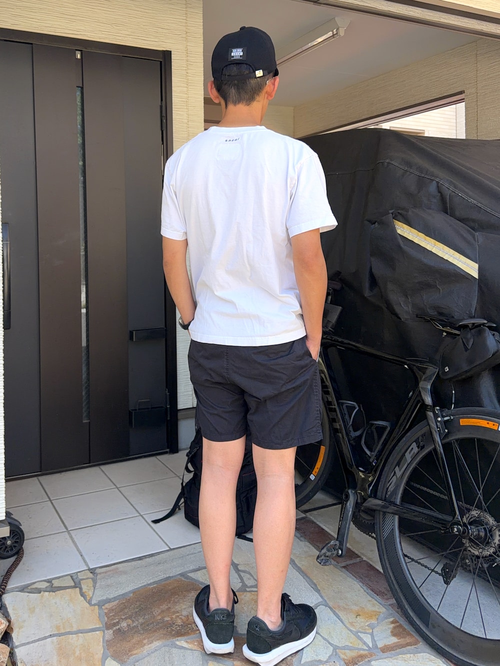 ブラック系のパンツ、ホワイト系のTシャツ/カットソー、ブラック系のスニーカーを着用したメンズの春コーディネートの2枚目の写真