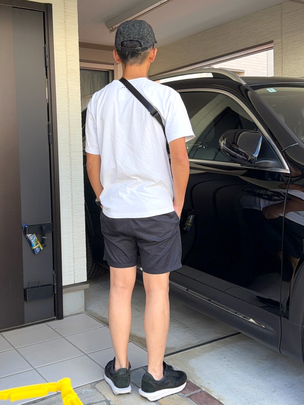 ホワイト系のTシャツ/カットソー、ブラック系のパンツ、ブラック系のスニーカーを着用したメンズの夏コーディネートの2枚目の写真