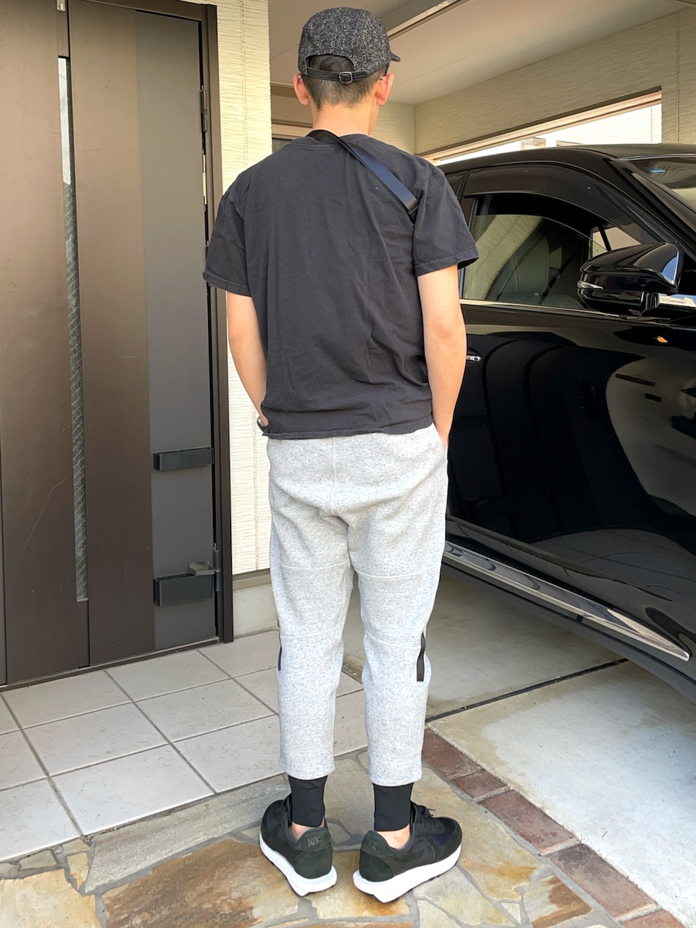 グレー系のスウェットパンツ、ブラック系のTシャツ/カットソー、ブラック系のボディバッグ/ウエストポーチを着用したメンズの春コーディネートの2枚目の写真