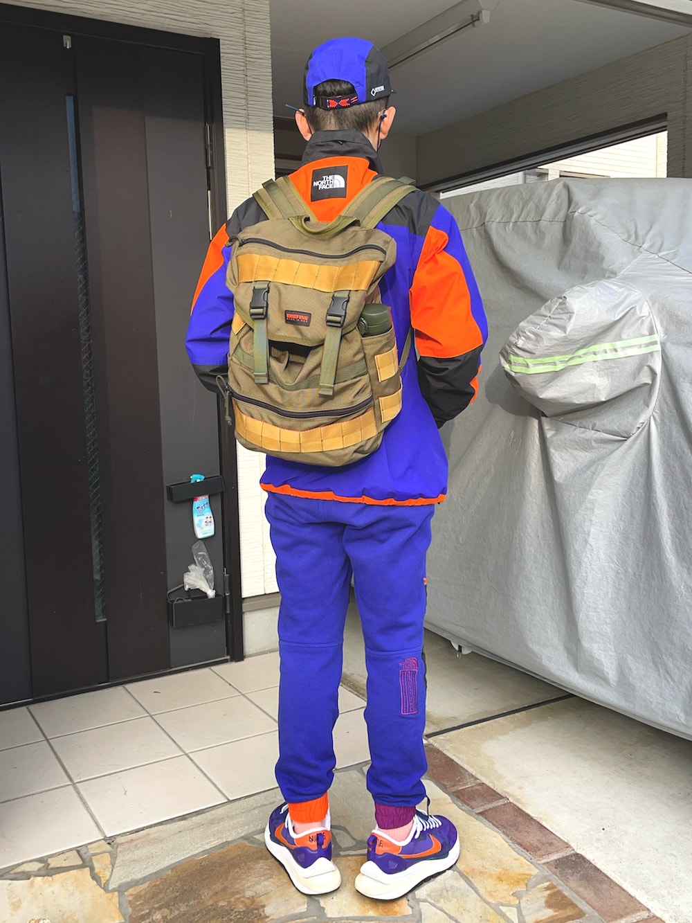 ブルー系のスウェットパンツ、パープル系のスニーカー、オレンジ系のナイロンジャケットを着用したメンズの冬コーディネートの2枚目の写真