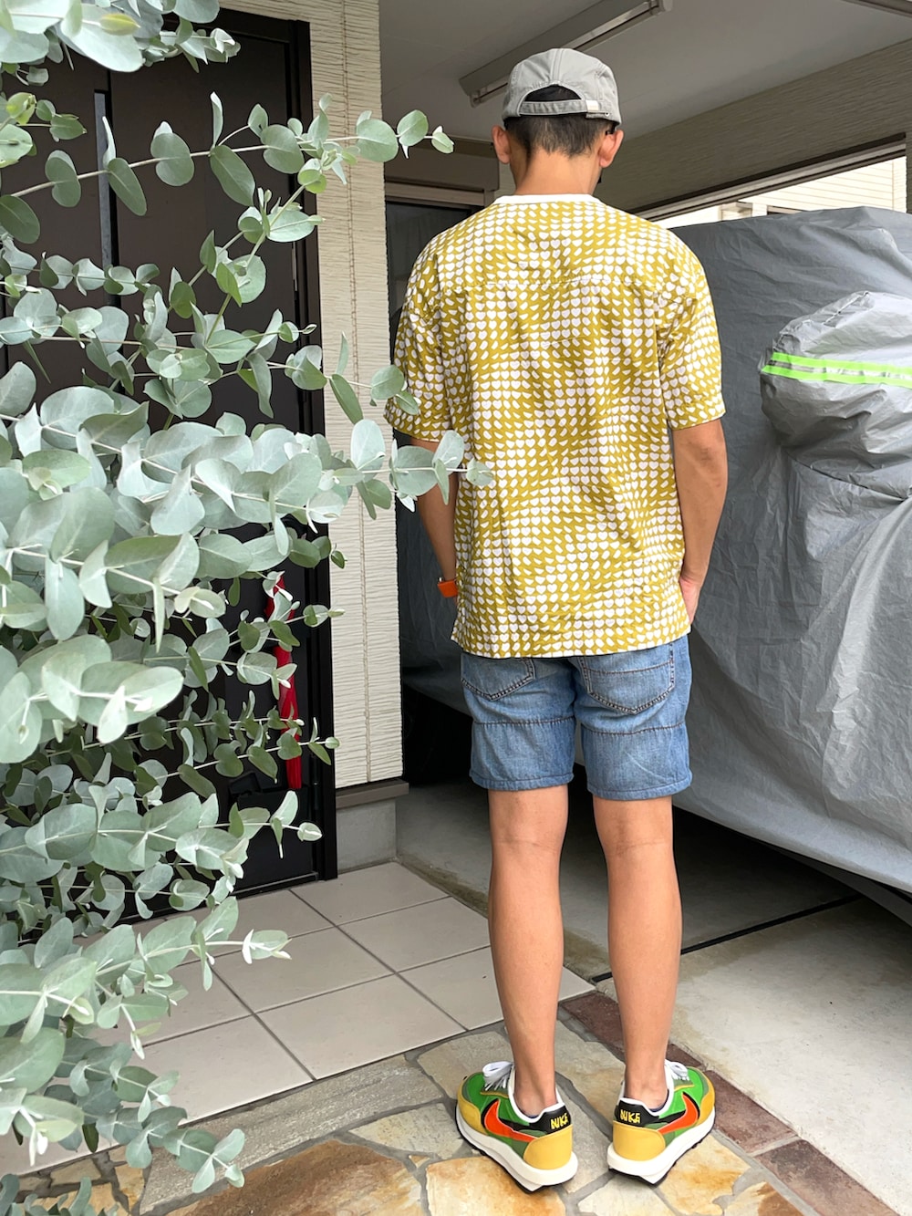 ベージュ系のTシャツ/カットソー、ブルー系のデニムパンツ、グリーン系のスニーカーを着用したメンズの夏コーディネートの2枚目の写真