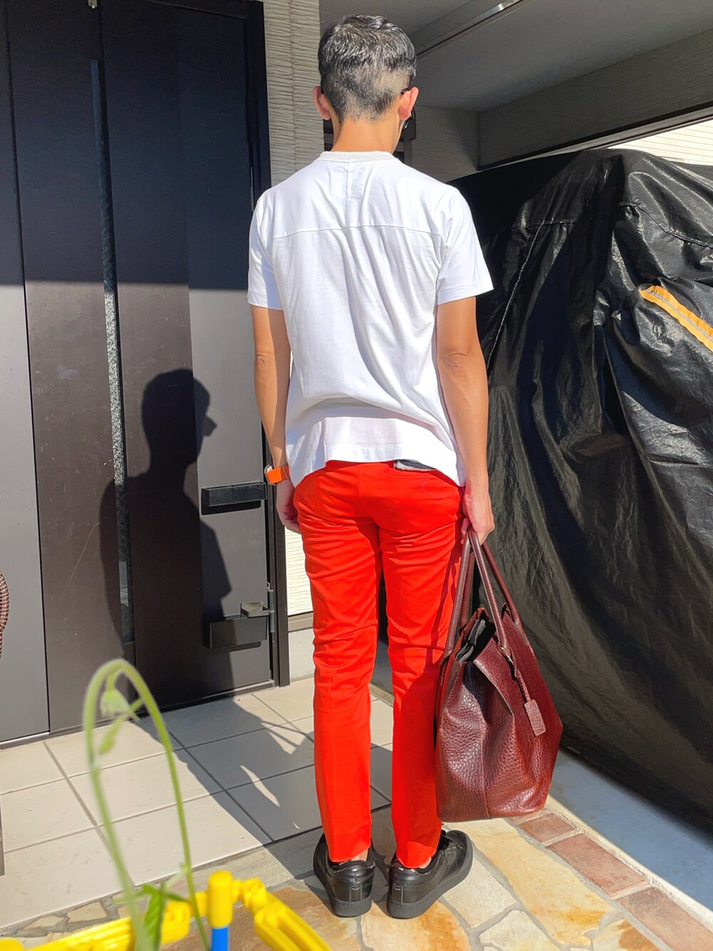 ホワイト系のTシャツ/カットソー、オレンジ系のスラックス、ブラック系のスニーカーを着用したメンズの夏コーディネートの2枚目の写真