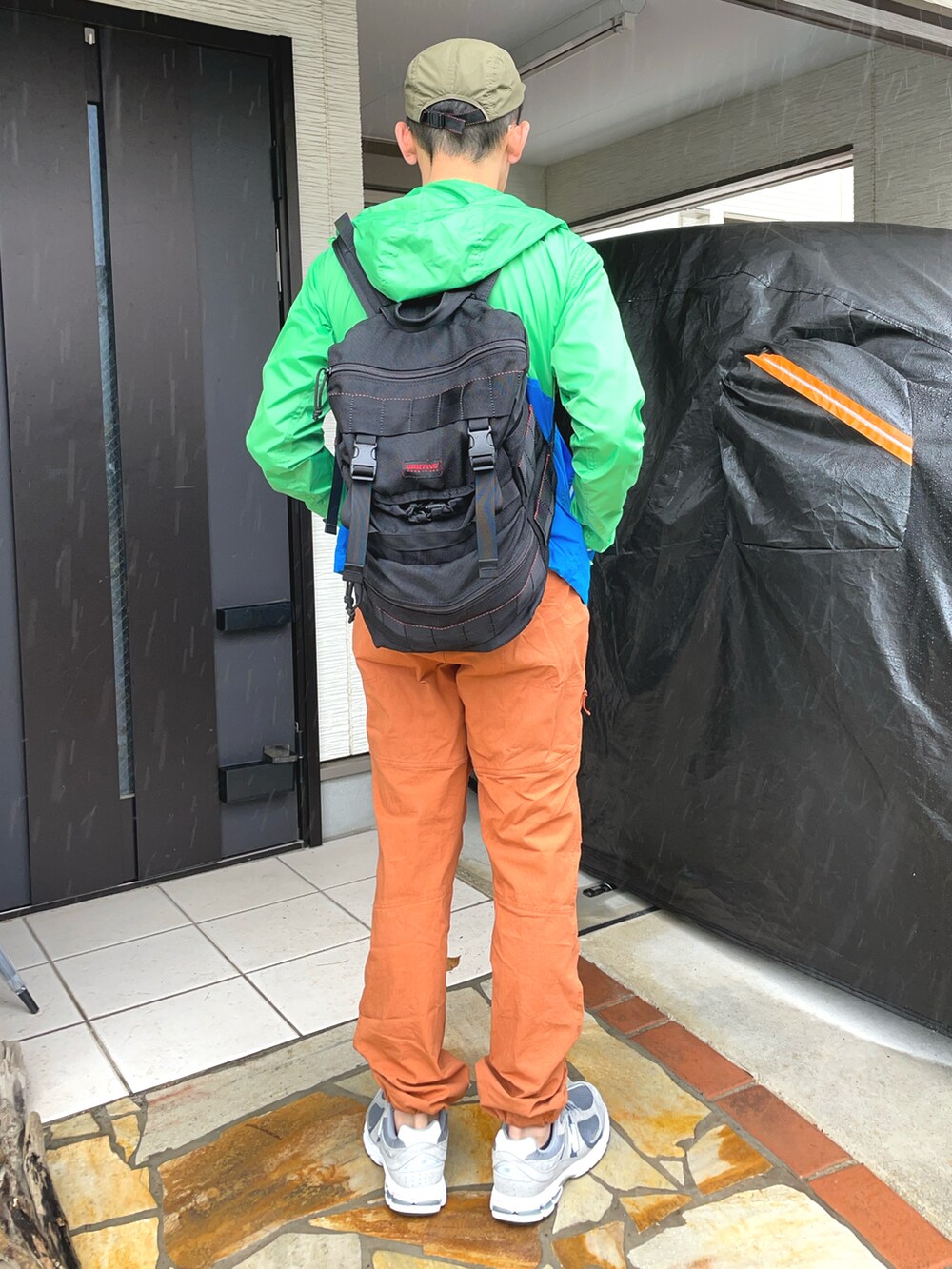 グレー系のスニーカー、オレンジ系のカーゴパンツ、グリーン系のナイロンジャケットを着用したメンズの春コーディネートの2枚目の写真