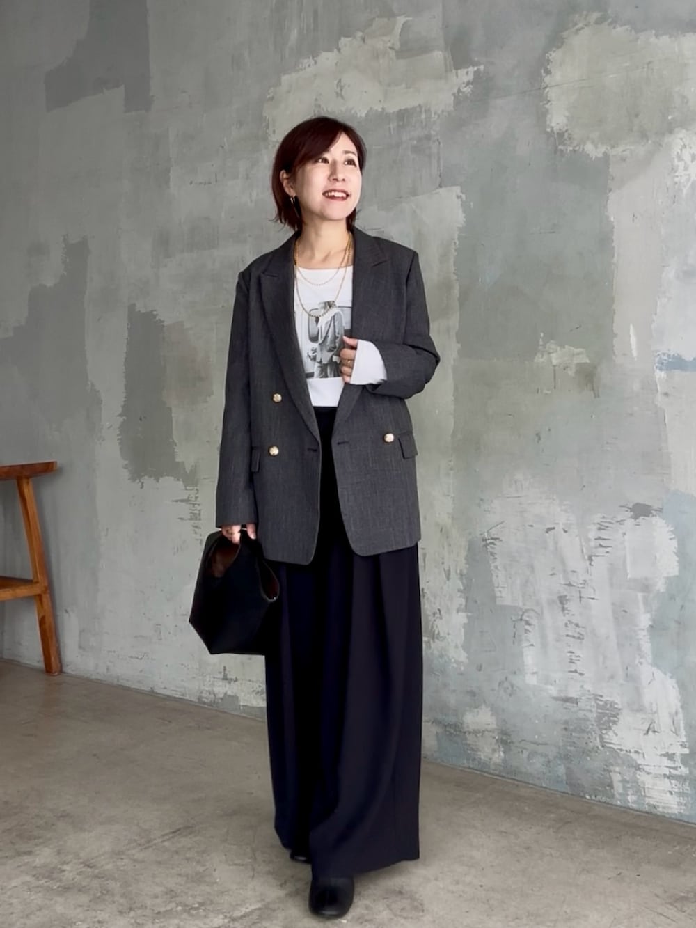 ブラック系のスラックス、ホワイト系のTシャツ/カットソー、グレー系のテーラードジャケットを着用したレディースの秋コーディネートの2枚目の写真