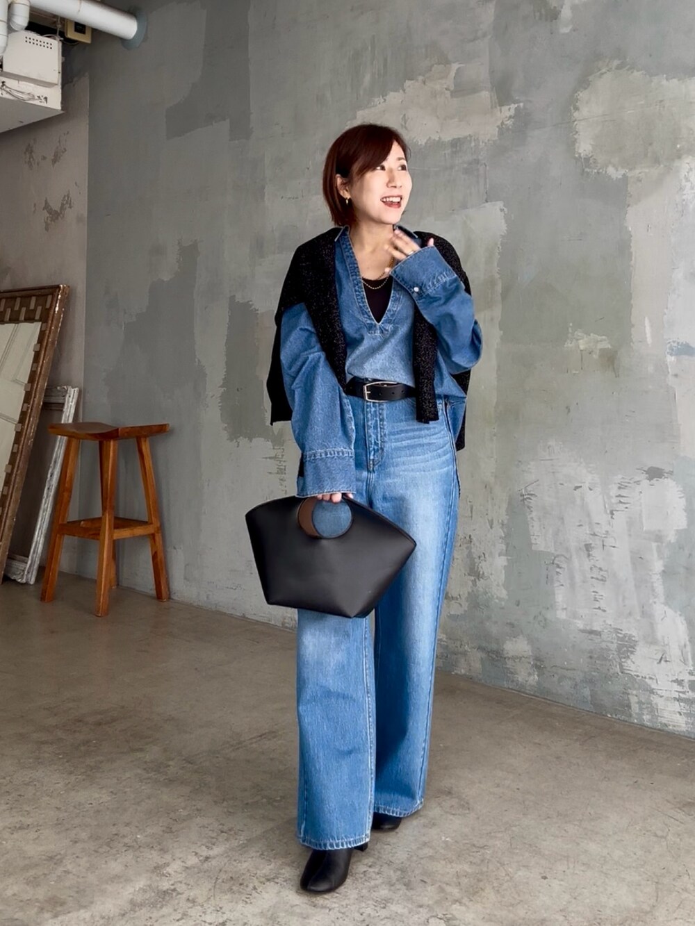 ブラック系のハンドバッグ、ブルー系のデニムパンツ、ブルー系のシャツ/ブラウスを着用したレディースの秋コーディネートの2枚目の写真