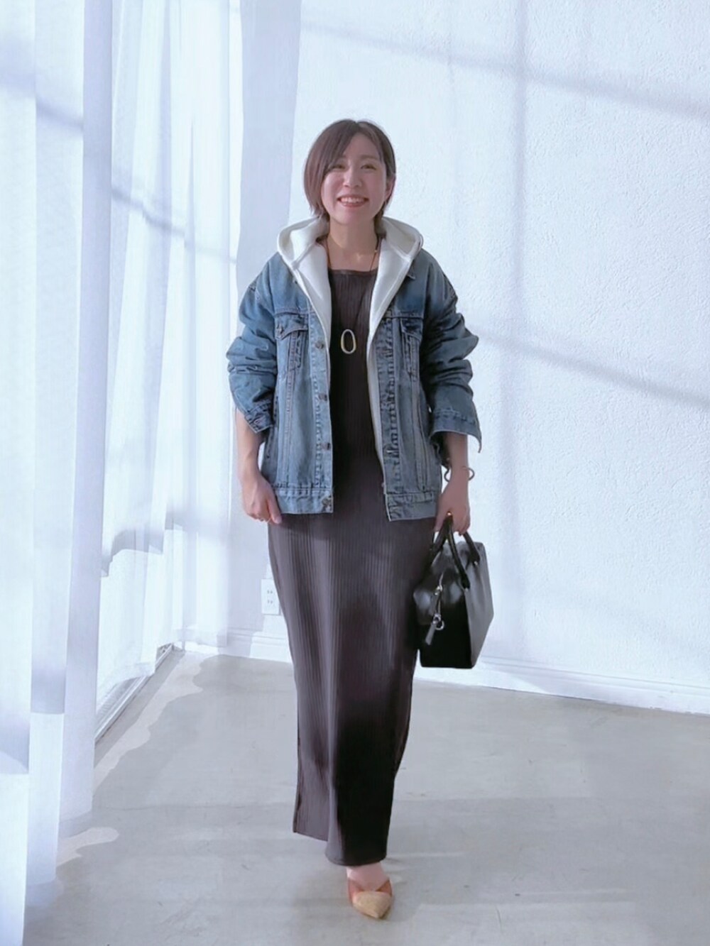 ブルー系のデニムジャケット、グレー系のワンピース、ブラウン系のパンプスを着用したレディースの冬コーディネートの3枚目の写真