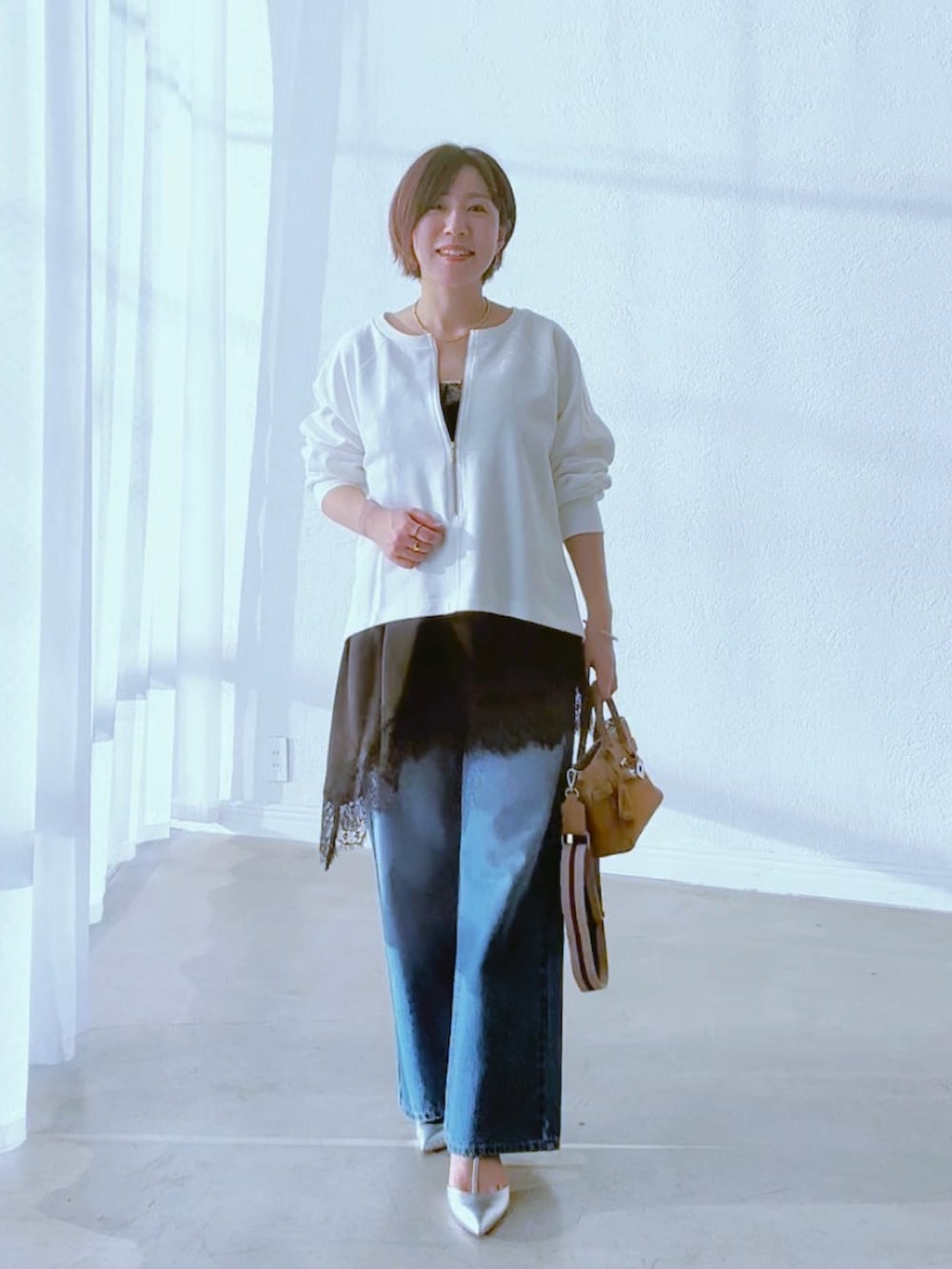 ホワイト系のスウェット、ブラック系のキャミソール、ブルー系のデニムパンツを着用したレディースの冬コーディネートの2枚目の写真