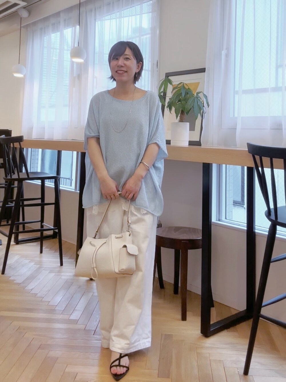 ホワイト系のデニムパンツ、ホワイト系のショルダーバッグ、ブルー系のニット/セーターを着用したレディースの春コーディネートの3枚目の写真