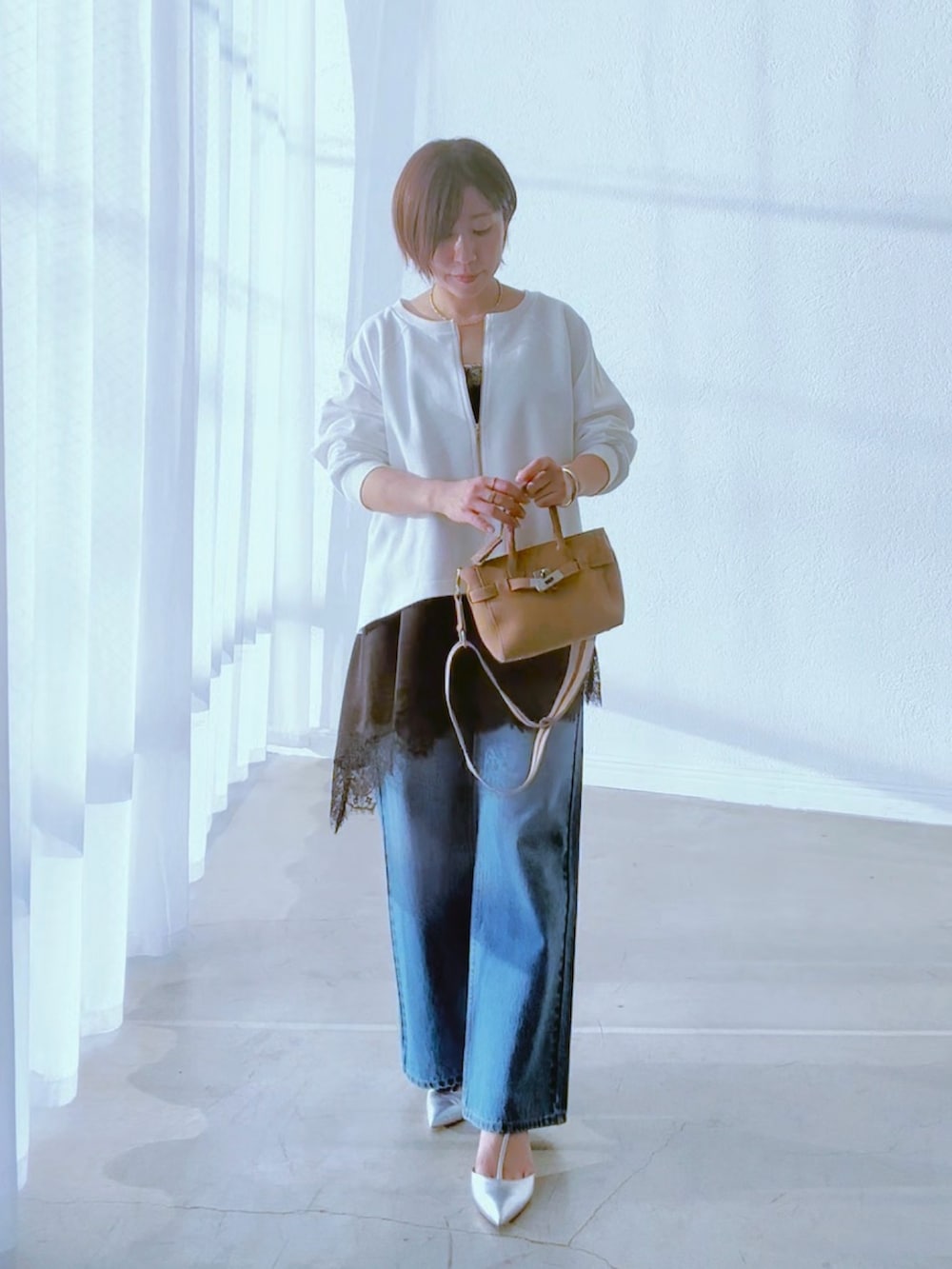 ホワイト系のスウェット、ブラック系のキャミソール、ブルー系のデニムパンツを着用したレディースの冬コーディネートの3枚目の写真