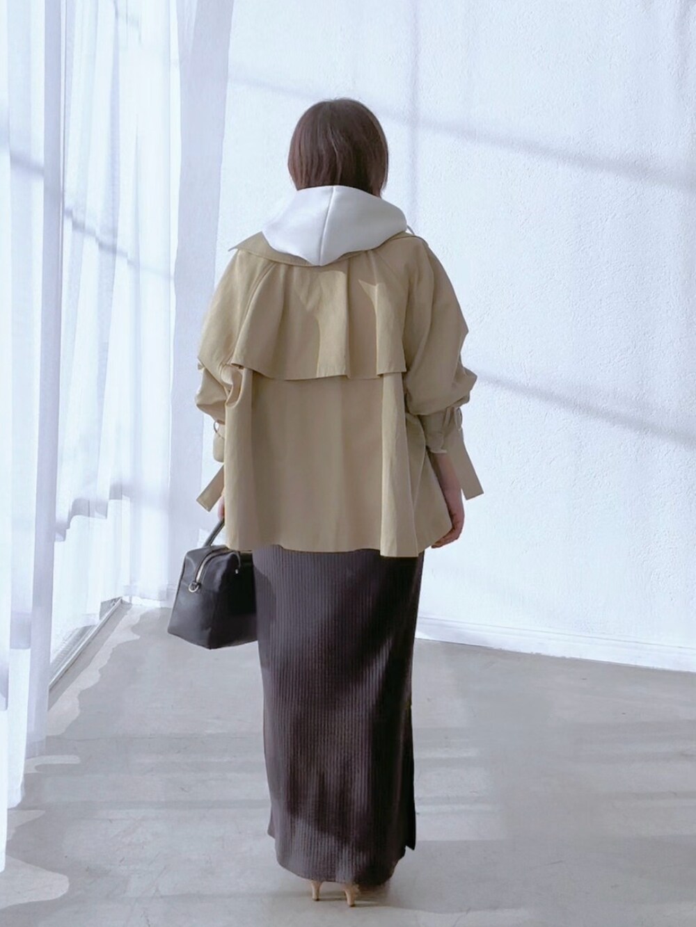 ベージュ系のトレンチコート、グレー系のワンピース、ホワイト系のパーカーを着用したレディースの冬コーディネートの5枚目の写真