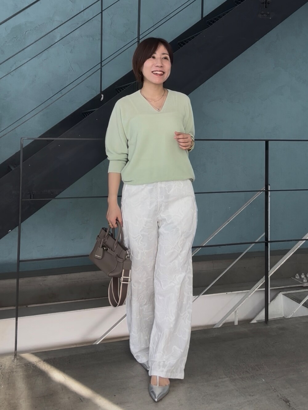 グリーン系のニット/セーター、グレー系のトートバッグ、シルバー系のその他シューズを着用したレディースの冬コーディネートの2枚目の写真