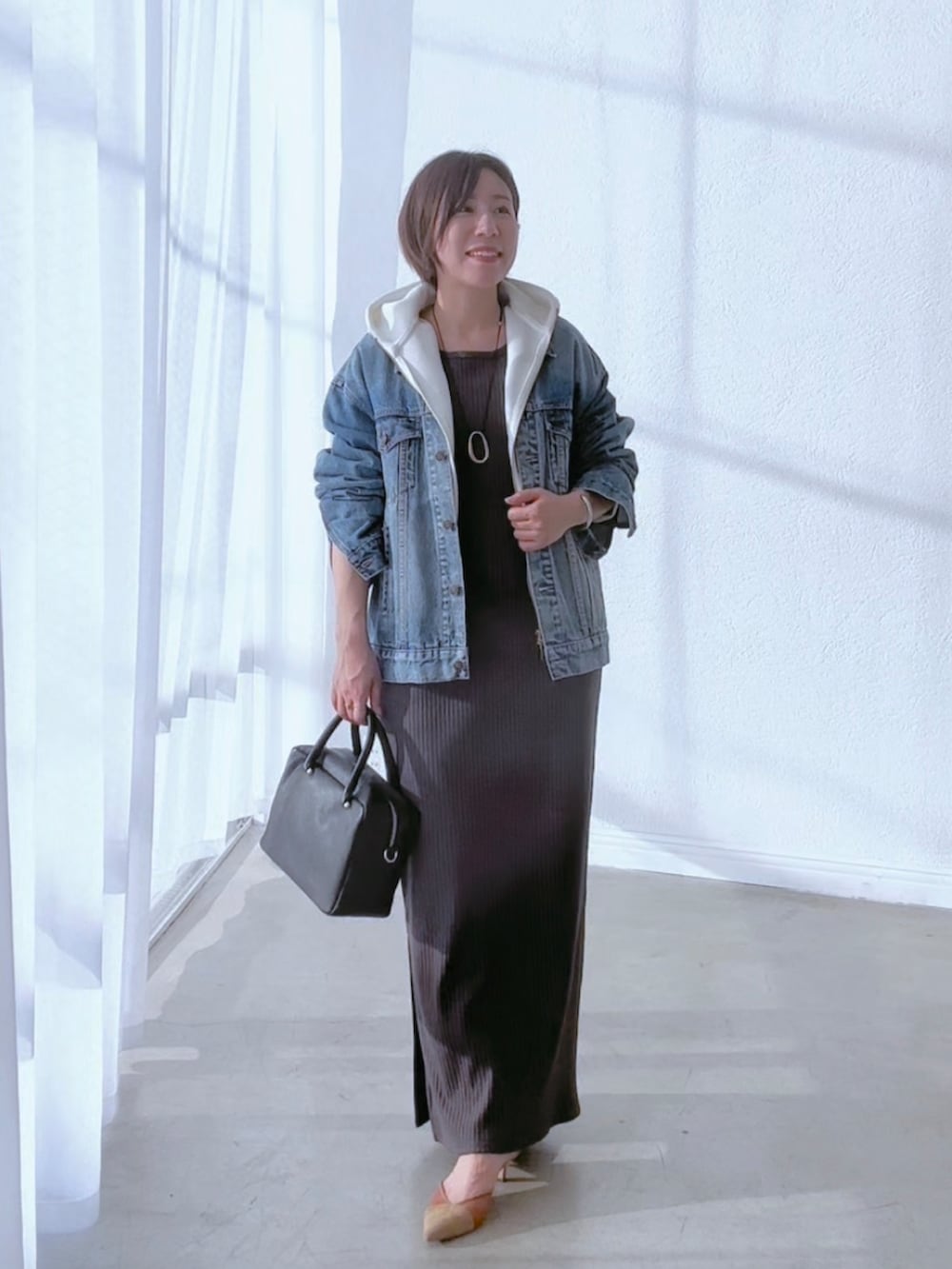 ブルー系のデニムジャケット、グレー系のワンピース、ブラウン系のパンプスを着用したレディースの冬コーディネートの2枚目の写真