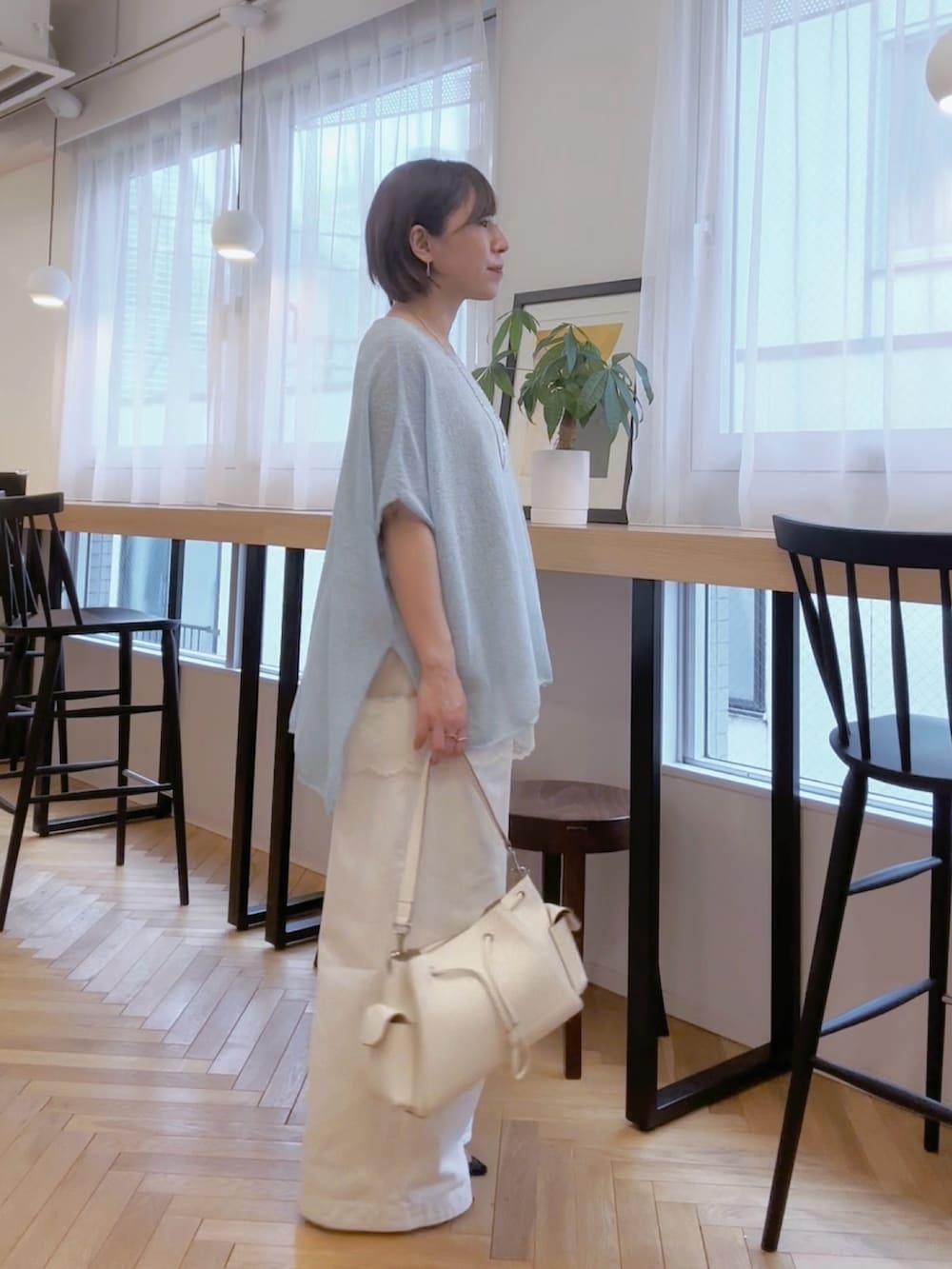 ホワイト系のデニムパンツ、ホワイト系のショルダーバッグ、ブルー系のニット/セーターを着用したレディースの春コーディネートの4枚目の写真