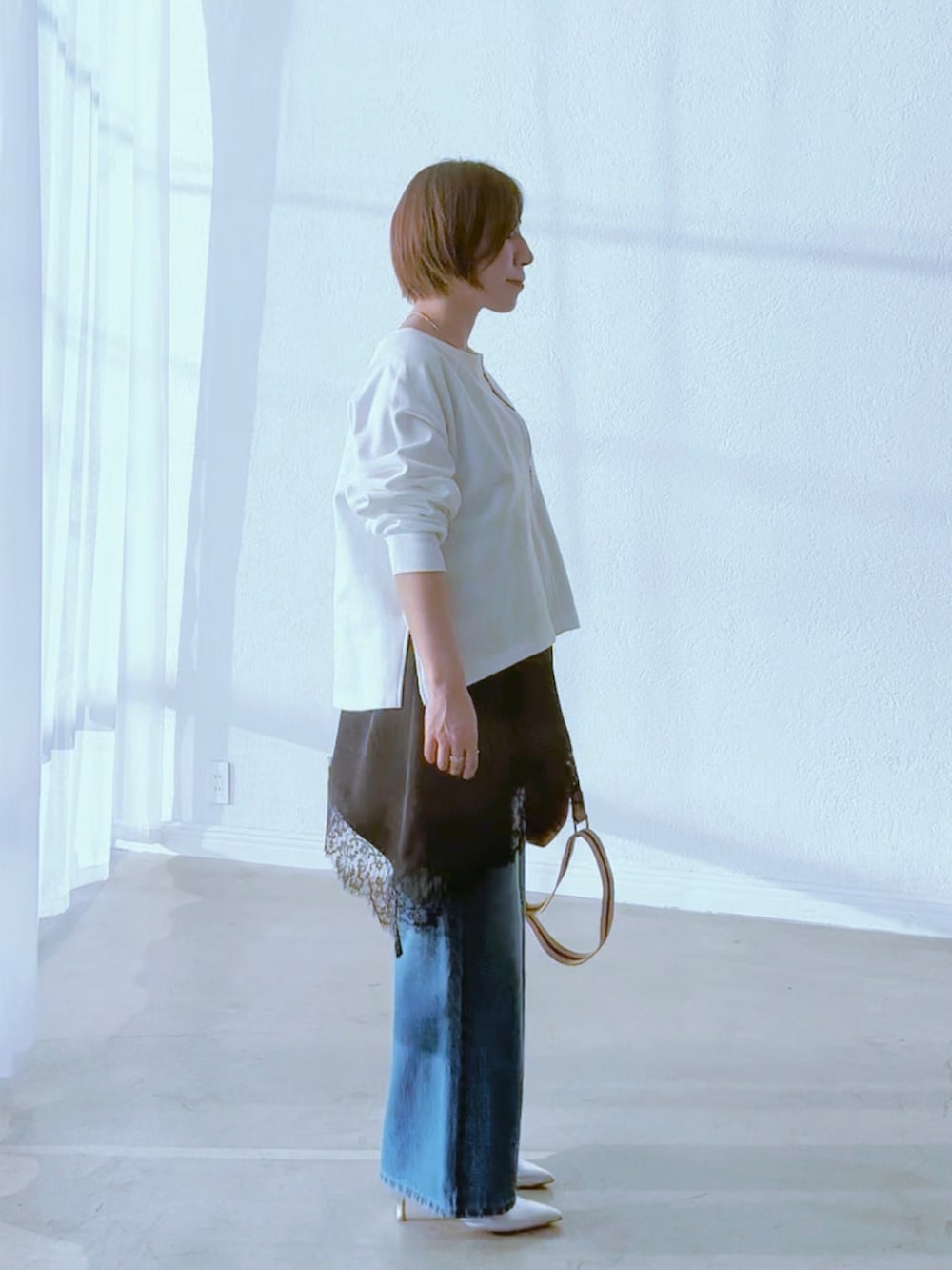 ホワイト系のスウェット、ブラック系のキャミソール、ブルー系のデニムパンツを着用したレディースの冬コーディネートの4枚目の写真