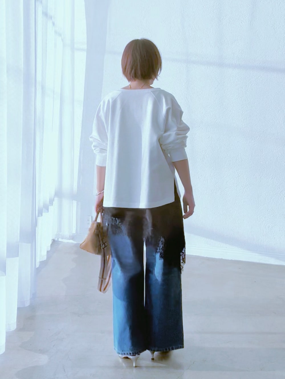 ホワイト系のスウェット、ブラック系のキャミソール、ブルー系のデニムパンツを着用したレディースの冬コーディネートの5枚目の写真