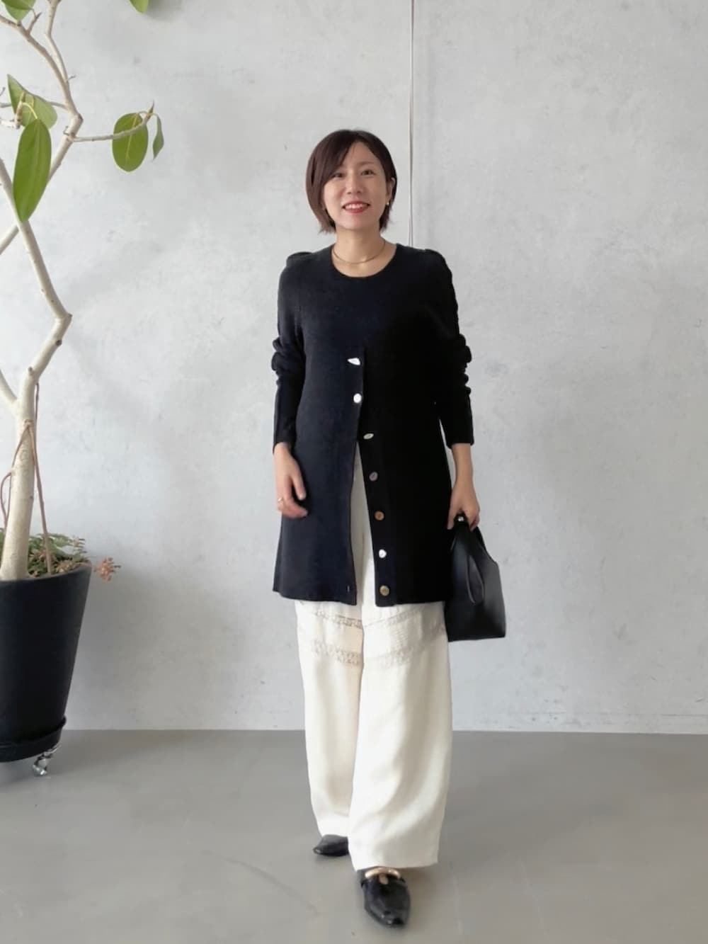 ホワイト系のその他パンツ、ブラック系のハンドバッグ、ブラック系のその他シューズを着用したレディースの冬コーディネートの2枚目の写真