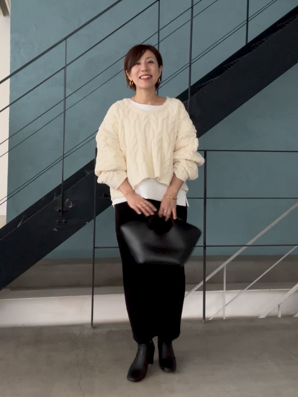 ホワイト系のニット/セーター、ホワイト系のTシャツ/カットソー、ブラック系のスカートを着用したレディースの秋コーディネートの2枚目の写真