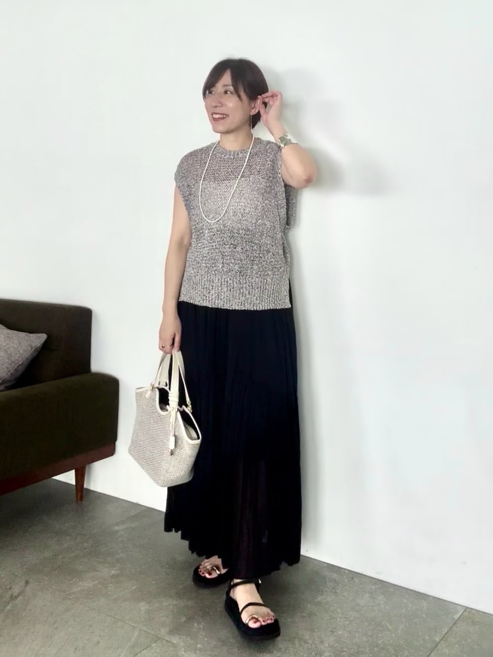 ブラック系のニット/セーター、ブラック系のスカート、ブラック系のサンダルを着用したレディースの夏コーディネートの3枚目の写真