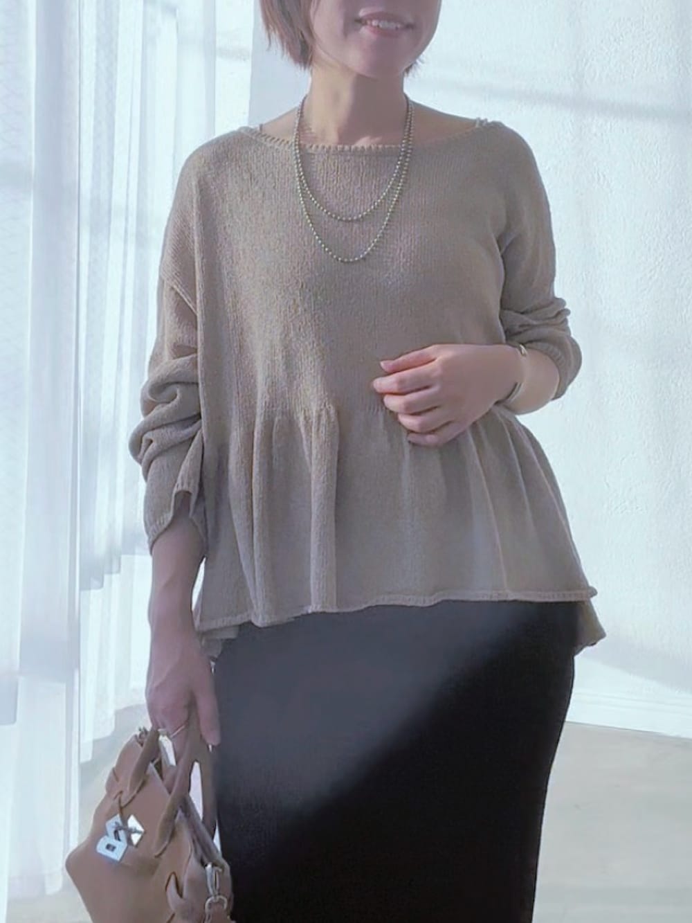 ブラック系のスカート、ブラウン系のパンプス、ベージュ系のトートバッグを着用したレディースの春コーディネートの4枚目の写真