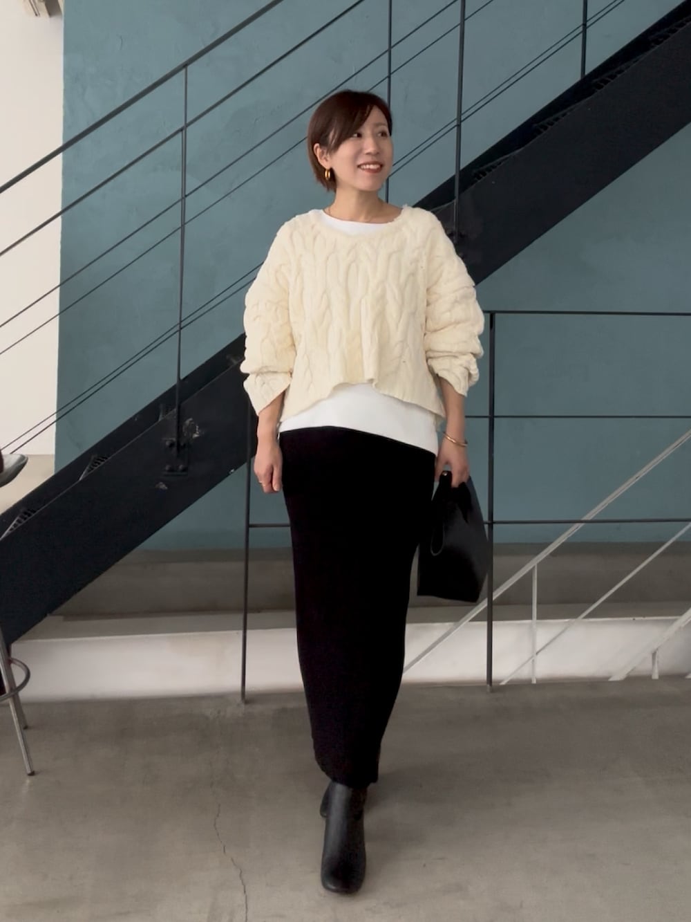 ホワイト系のニット/セーター、ホワイト系のTシャツ/カットソー、ブラック系のスカートを着用したレディースの秋コーディネートの3枚目の写真