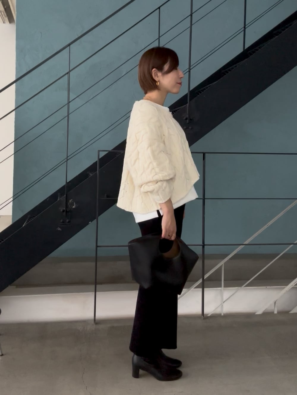 ホワイト系のニット/セーター、ホワイト系のTシャツ/カットソー、ブラック系のスカートを着用したレディースの秋コーディネートの4枚目の写真