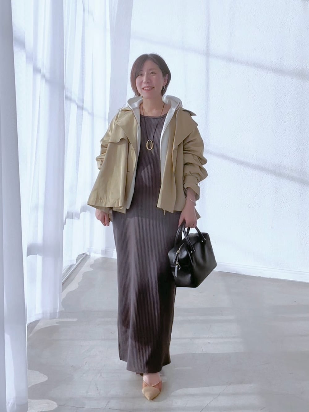 ベージュ系のトレンチコート、グレー系のワンピース、ホワイト系のパーカーを着用したレディースの冬コーディネートの3枚目の写真