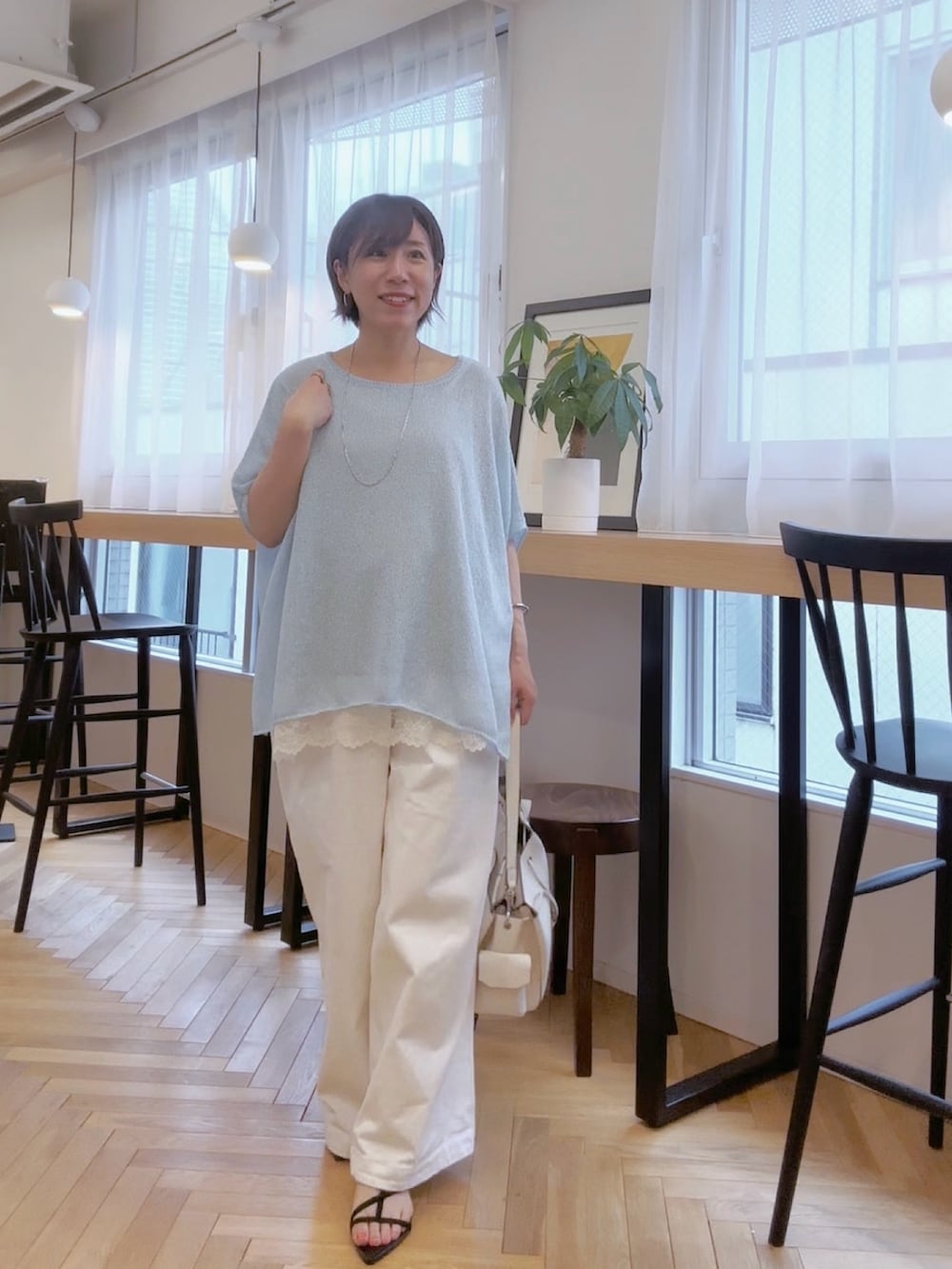 ホワイト系のデニムパンツ、ホワイト系のショルダーバッグ、ブルー系のニット/セーターを着用したレディースの春コーディネートの2枚目の写真