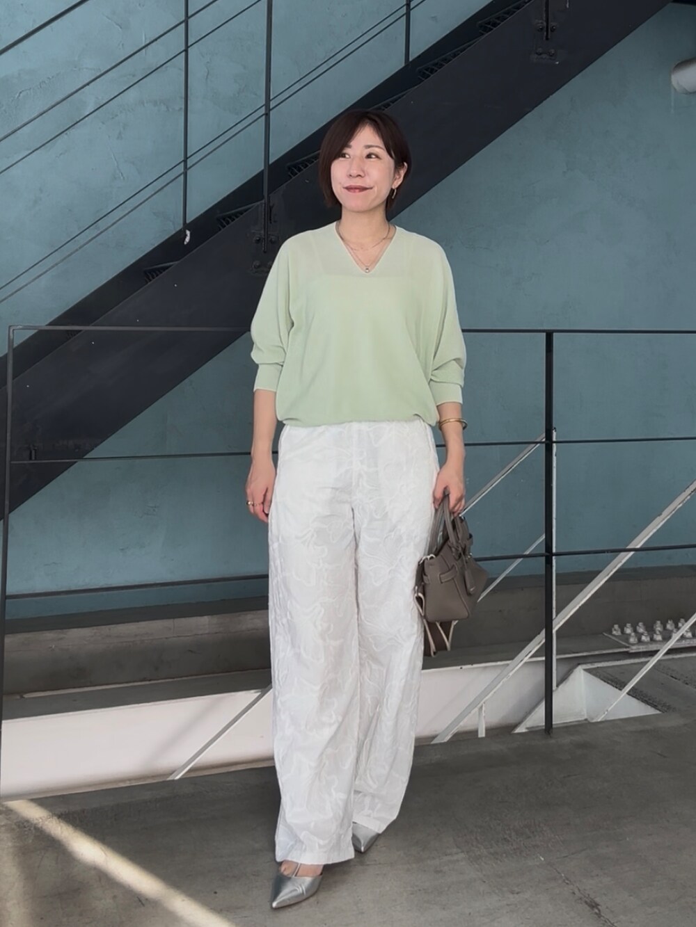 グリーン系のニット/セーター、グレー系のトートバッグ、シルバー系のその他シューズを着用したレディースの冬コーディネートの3枚目の写真