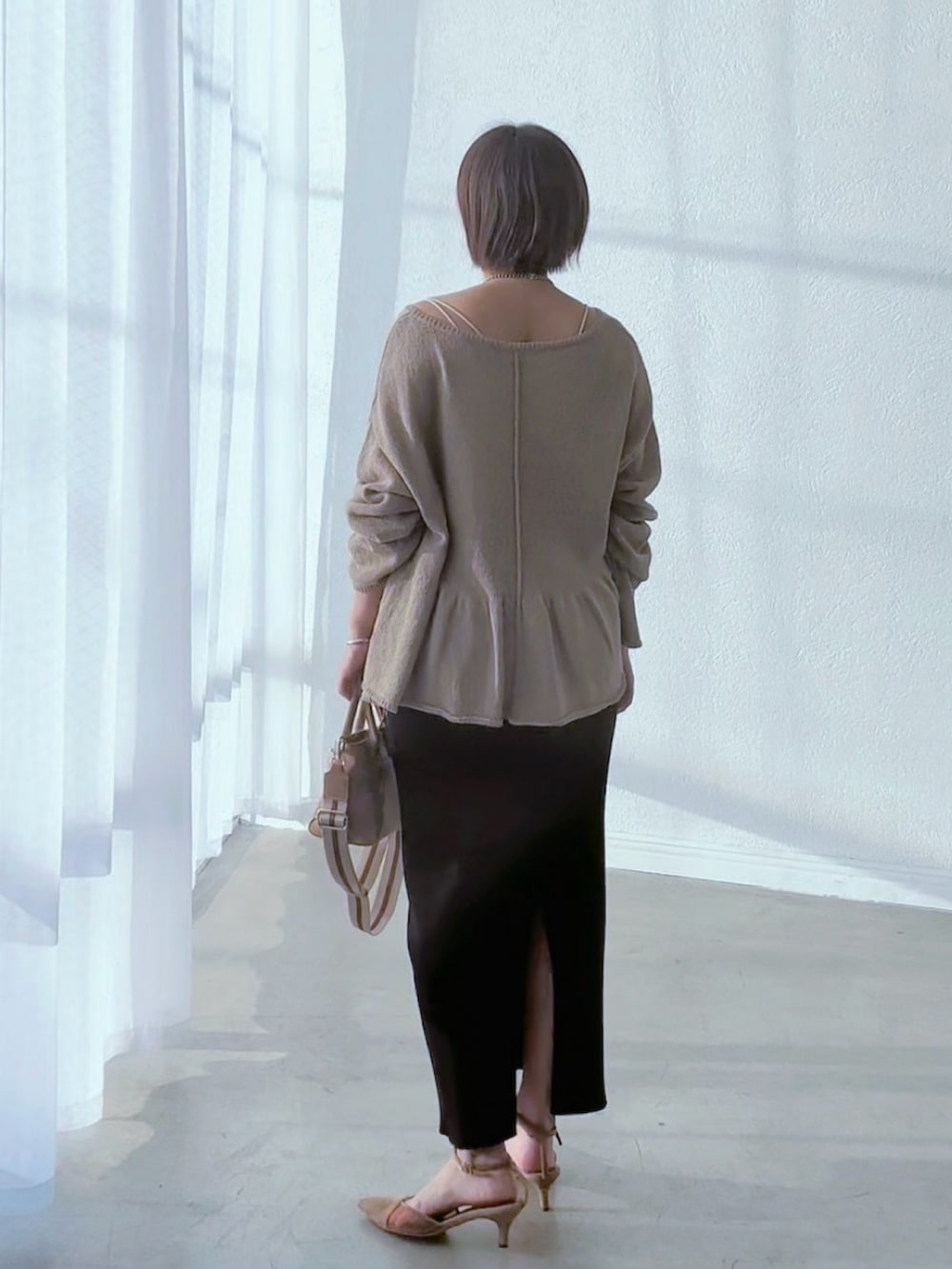 ブラック系のスカート、ブラウン系のパンプス、ベージュ系のトートバッグを着用したレディースの春コーディネートの3枚目の写真