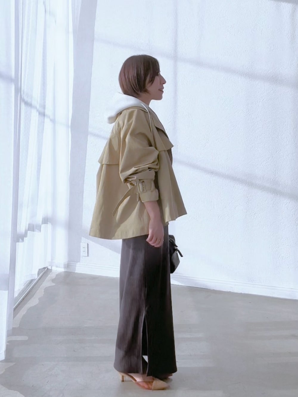 ベージュ系のトレンチコート、グレー系のワンピース、ホワイト系のパーカーを着用したレディースの冬コーディネートの4枚目の写真