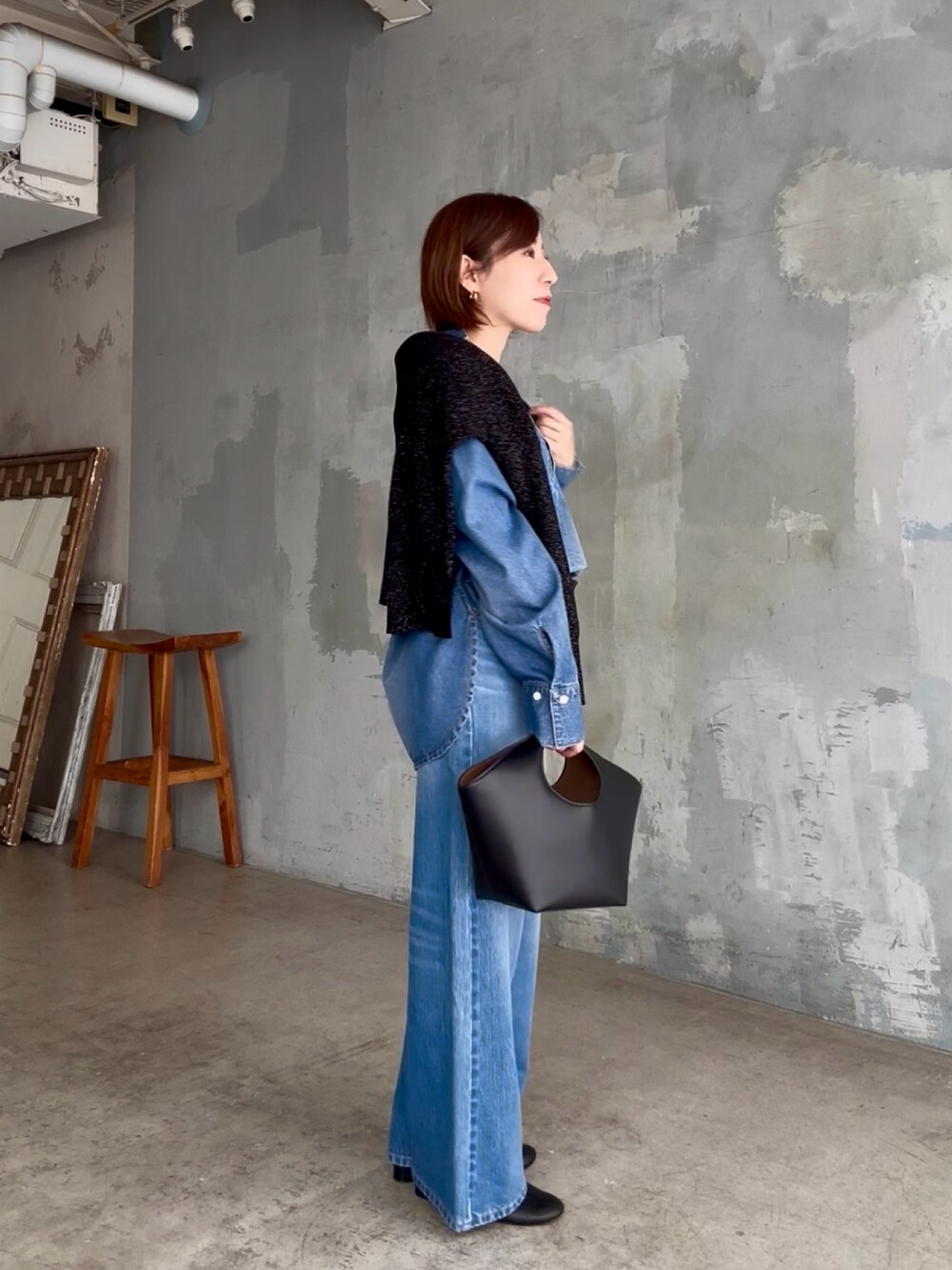 ブラック系のハンドバッグ、ブルー系のデニムパンツ、ブルー系のシャツ/ブラウスを着用したレディースの秋コーディネートの3枚目の写真