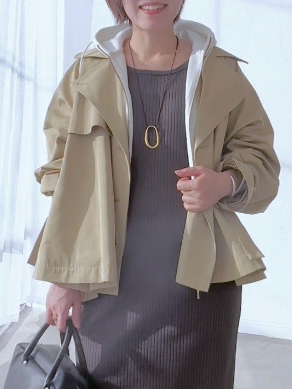 ベージュ系のトレンチコート、グレー系のワンピース、ホワイト系のパーカーを着用したレディースの冬コーディネートの6枚目の写真