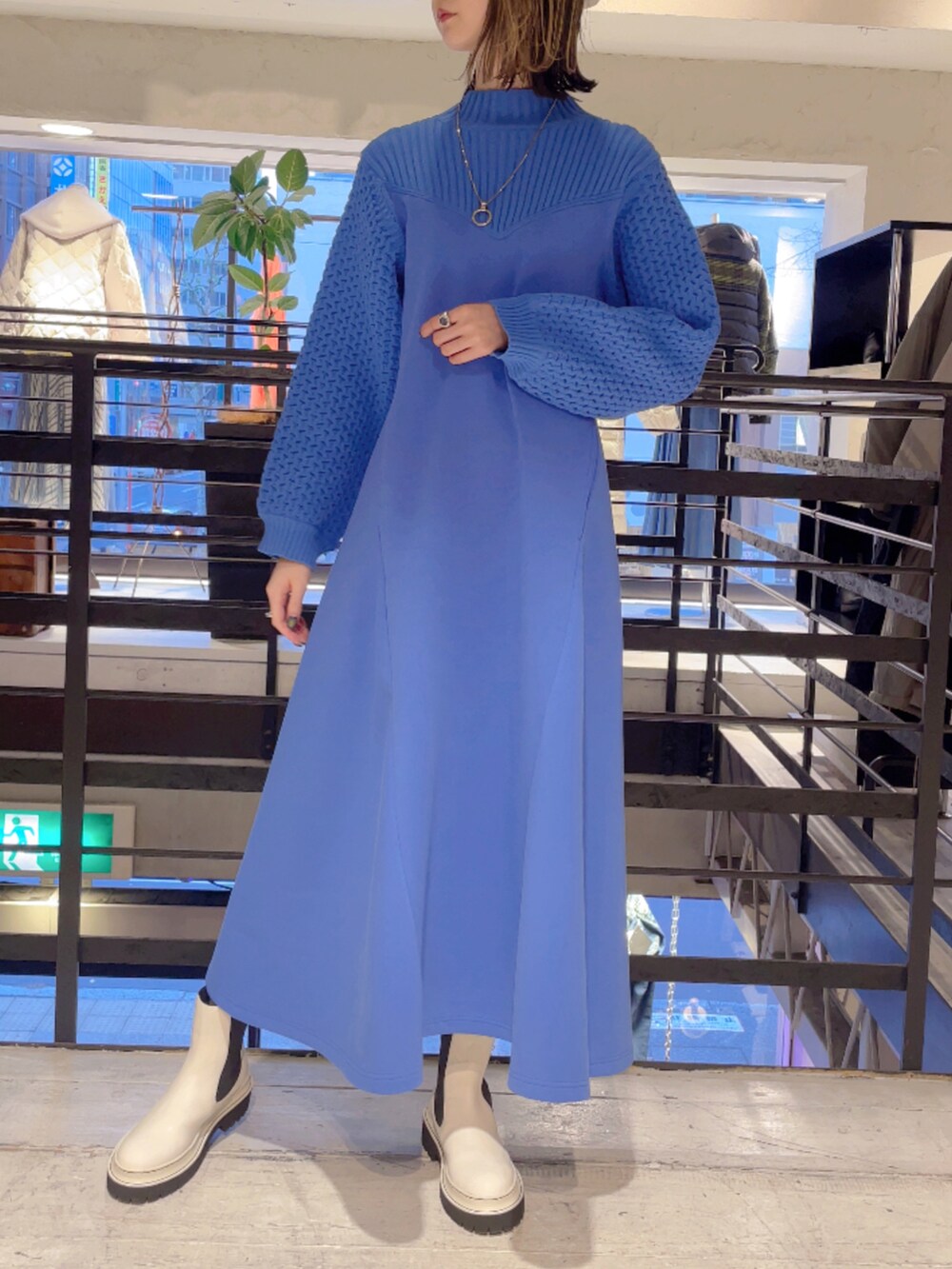 ブルー系のワンピース、ホワイト系のブーツ、シルバー系のネックレスを着用したレディースの冬コーディネートの2枚目の写真