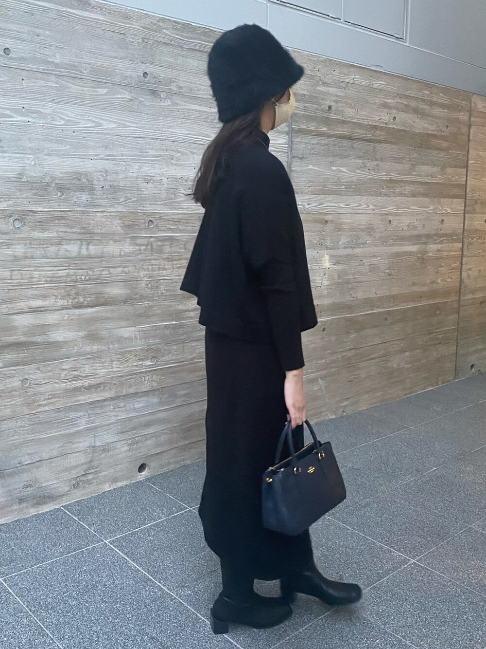 ブルー系のハンドバッグ、ブラック系のブーツ、ブラック系のワンピースを着用したレディースの冬コーディネートの2枚目の写真