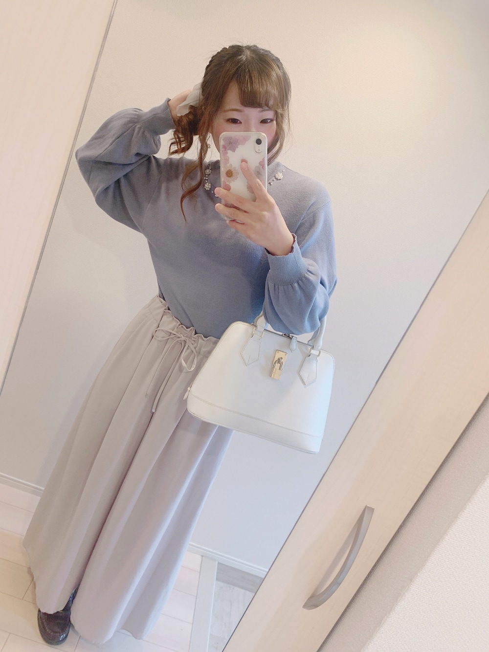 ホワイト系のハンドバッグ、ベージュ系のパンツ、ブルー系のニット/セーターを着用したレディースの秋コーディネートの2枚目の写真