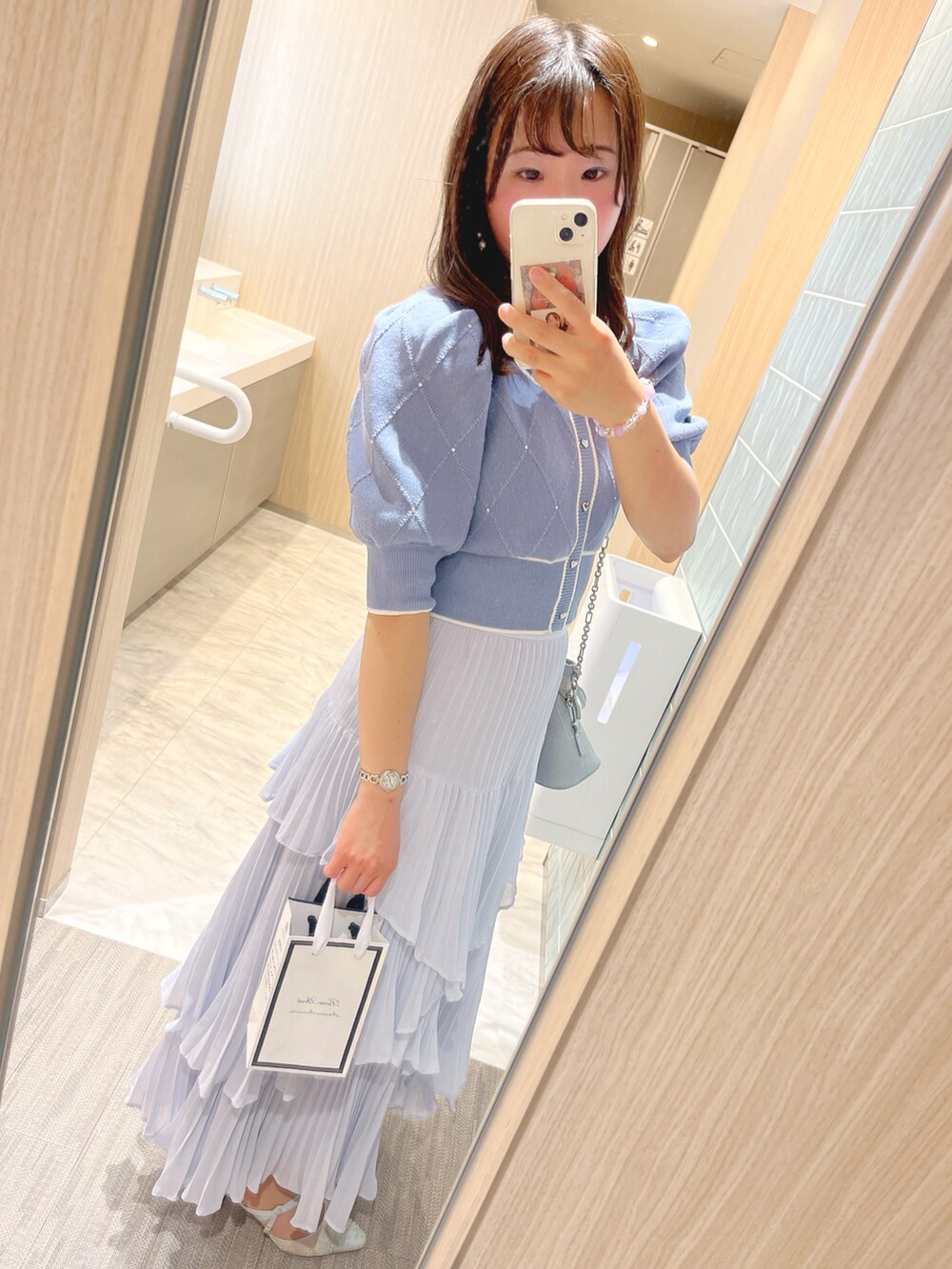 ブルー系のニット/セーター、ホワイト系のショルダーバッグ、ブルー系のスカートを着用したレディースの春コーディネートの3枚目の写真