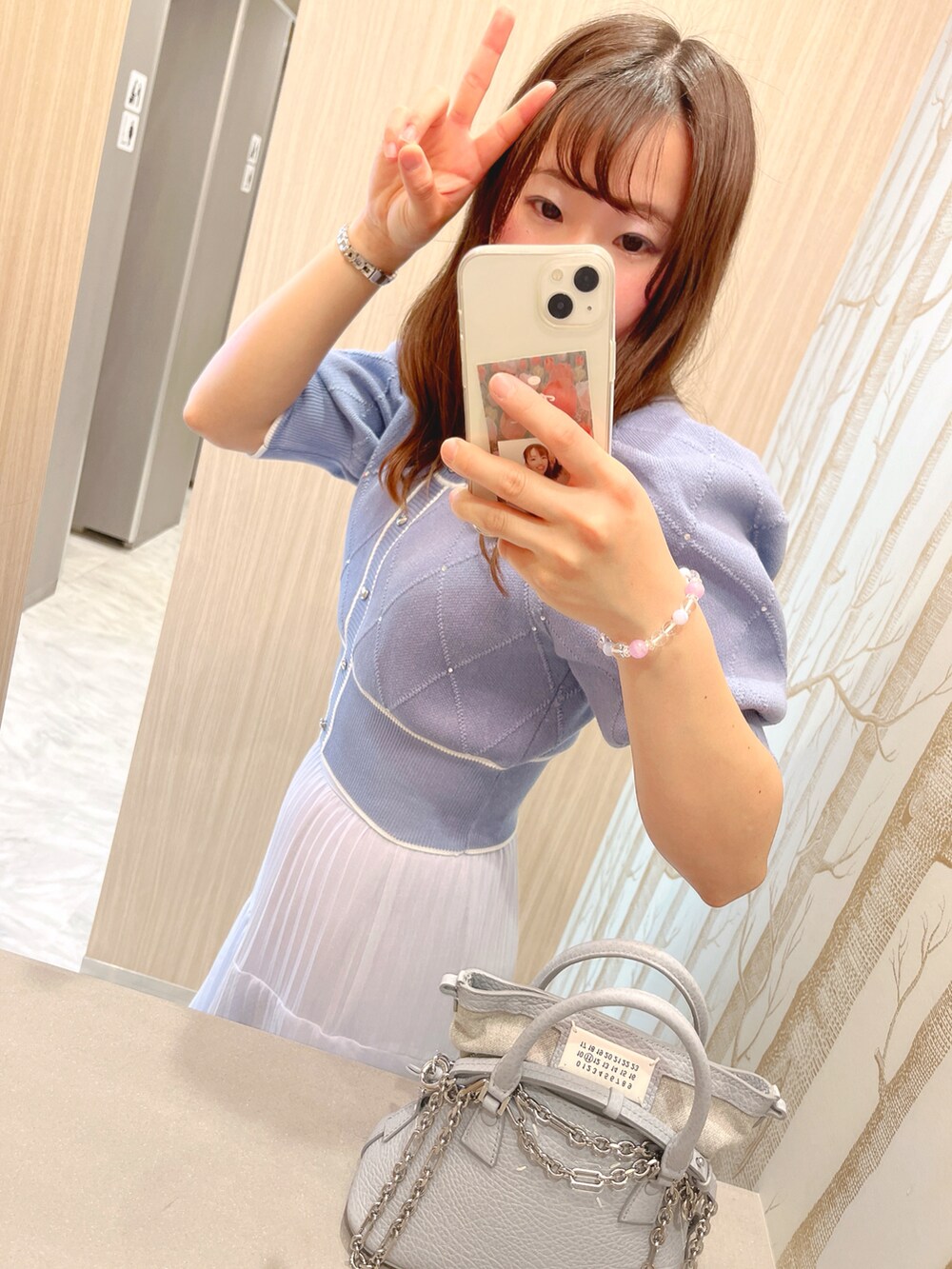 ブルー系のニット/セーター、ホワイト系のショルダーバッグ、ブルー系のスカートを着用したレディースの春コーディネートの2枚目の写真