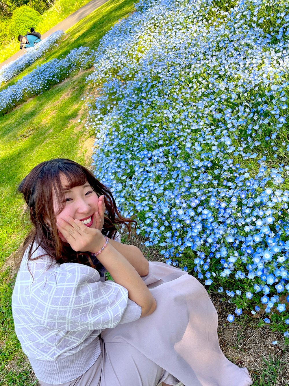 パープル系のニット/セーター、グレー系のスカート、ホワイト系のパンプスを着用したレディースの春コーディネートの2枚目の写真